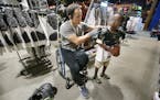 Chuck Aoki, a paralympic rugby player, helped Givenson Thimjon, 6, cq, with shoulder pads during his shift at Dick's Sporting Goods, Friday, July 15, 