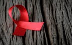 Red ribbon on wooden background for World Aids day awareness campaign.