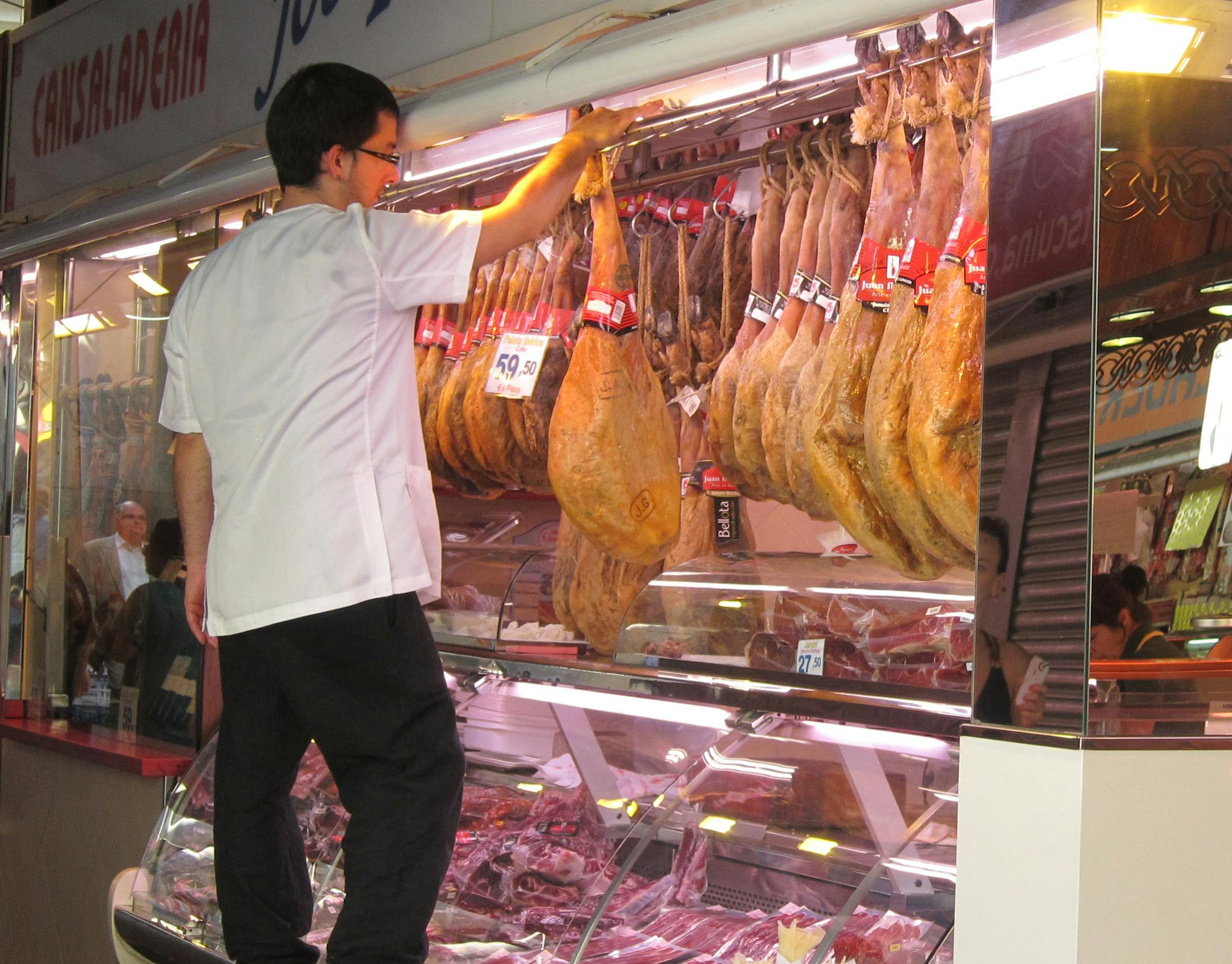 A vendor hangs hams at Boqueria Market. Wesley K.H. Teo