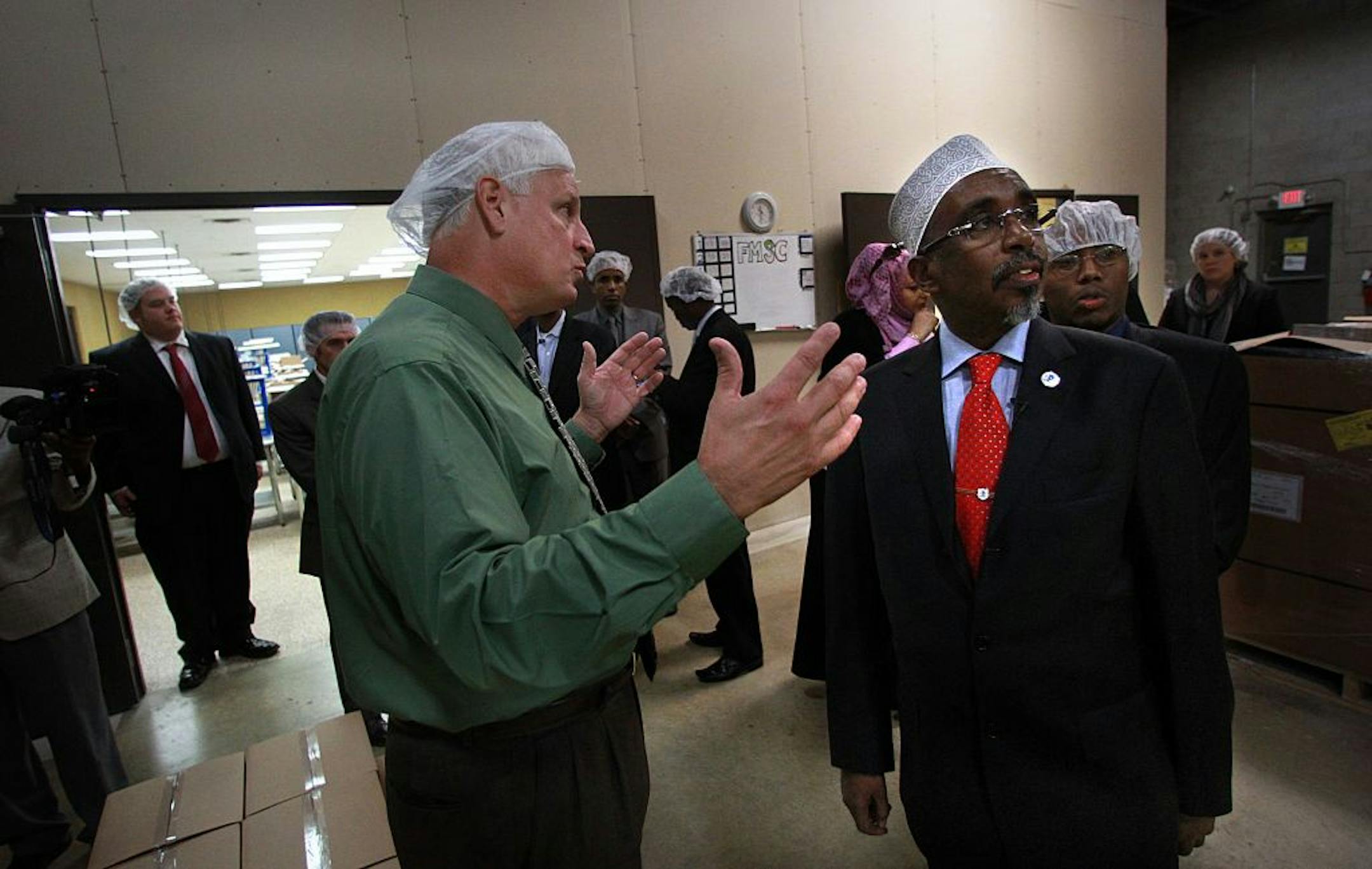 Sharif Hassan Sheikh Aden, speaker of the Transitional Federal Parliament of Somalia (right, foreground) and several others were escorted on a tour of the Feed My Starving Children (FMSC) headquarters in Coon Rapids, by the organization's CEO, Mark Crea (left, middle). FSMC has sent thousands of volunteer-packed meals to people affected by famine in Somalia and other areas of the world.