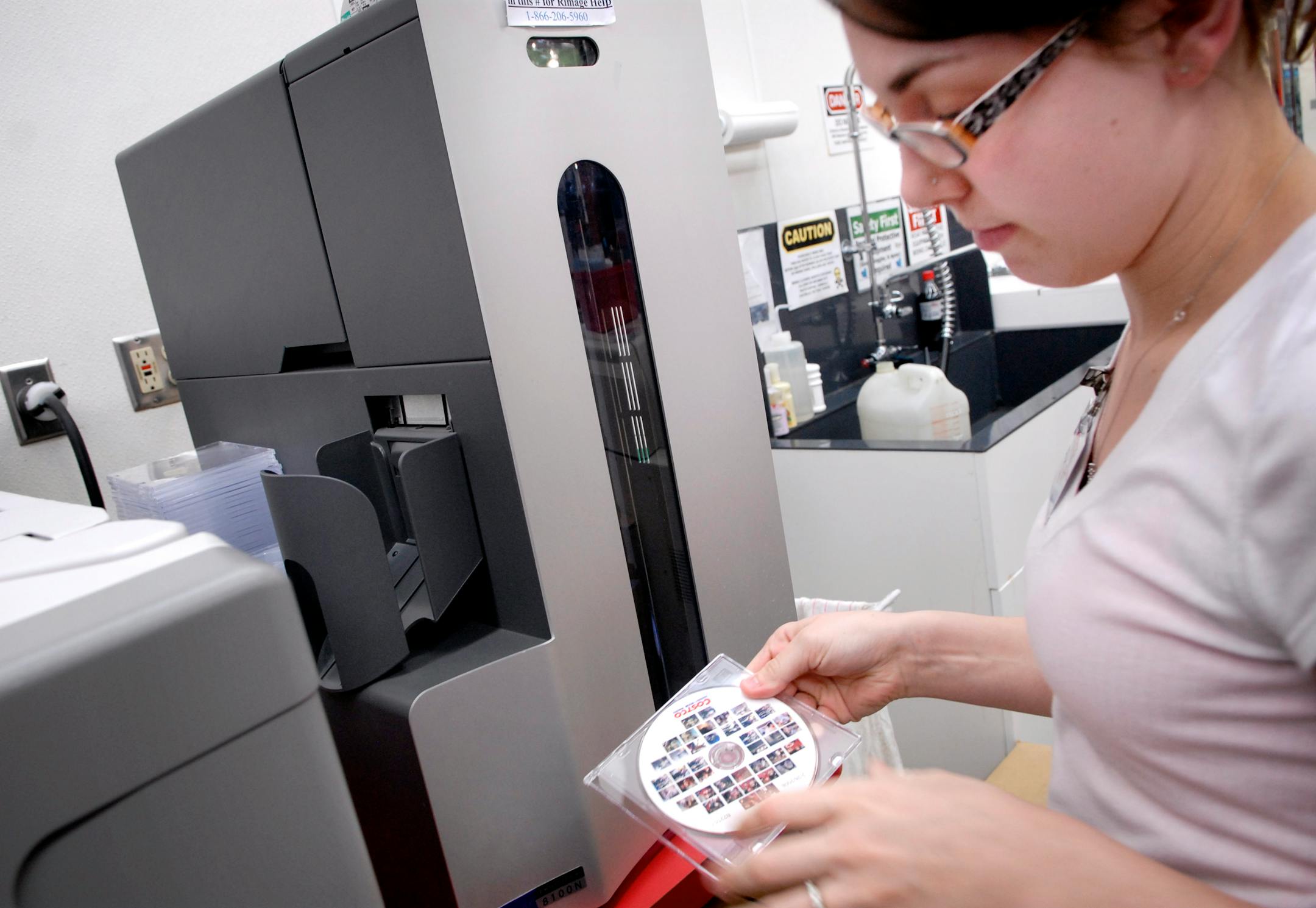 Ashley Lanigan used a system manufactured by Rimage Corp. to put a customer's photos on an image CD at the St. Louis Park Costco. The machine can also burn the images to a DVD or a Blu-ray disc. They are printed as thumbnails on the cover using thermal imaging.