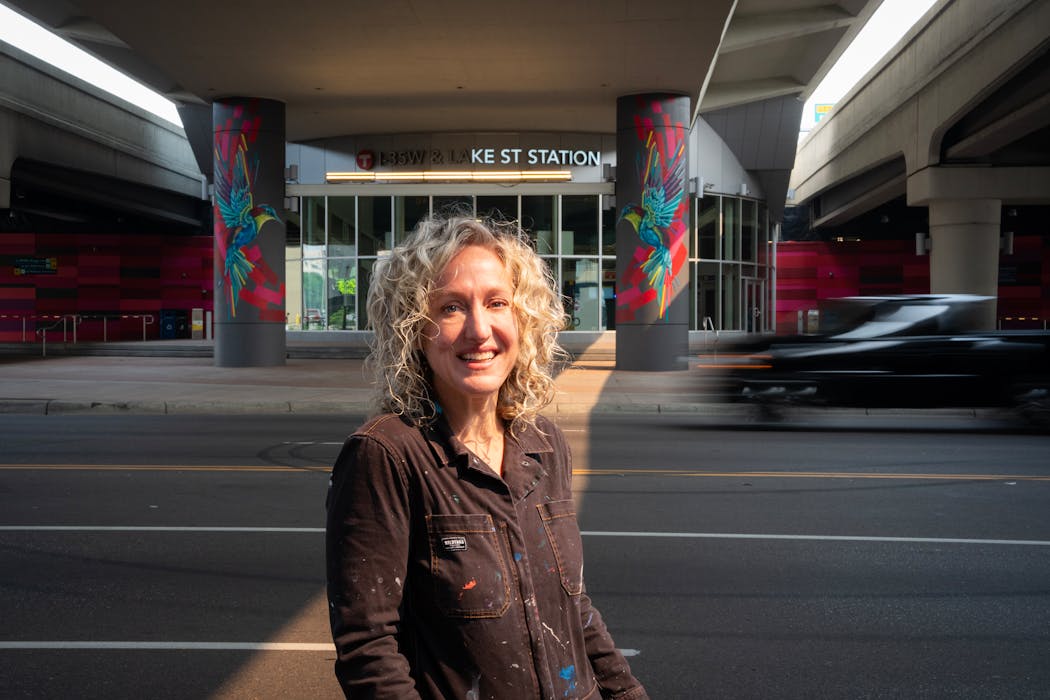 Artist Kada Goalen stands in front of the mural she created on the walls surrounding the Lake Street and 35W transit station in Minneapolis, Minn., on Saturday, July 15, 2023.