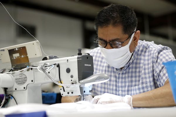 Jose Pedro Sanchez,a seamstress at Blue Delta Jeans, sews together a face guard at the jeans manufacturing company's site in Shannon, Miss. (AP Photo/