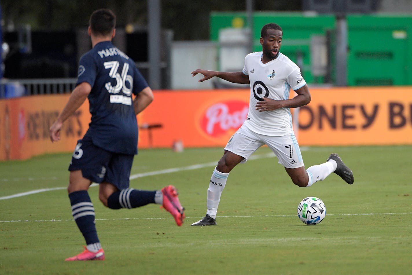 Minnesota United midfielder Kevin Molino (7) sets up a play in front of Sporting Kansas City defender Luis Martins (36) during the first half of an MLS soccer match, Sunday, July 12, 2020, in Kissimmee, Fla. (AP Photo/Phelan M. Ebenhack)