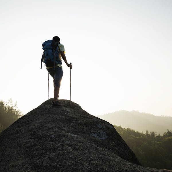 Male hiker standing on a rock of mountain peak.