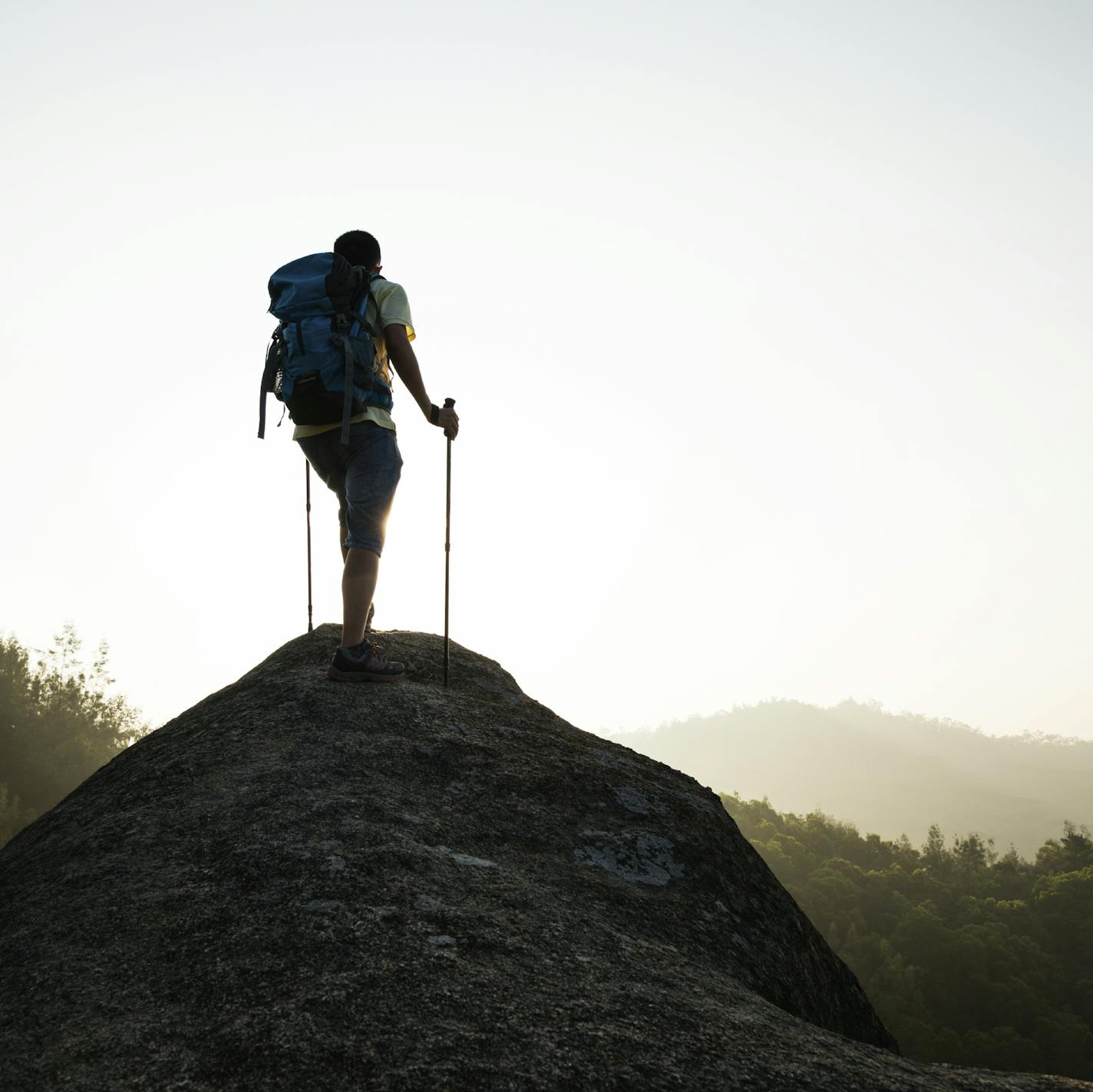 Male hiker standing on a rock of mountain peak.