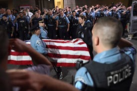 Law enforcement officers salute the flag-draped remains of fallen Minneapolis police Officer Jamal Mitchell on May 30. Mitchell was killed earlier in 