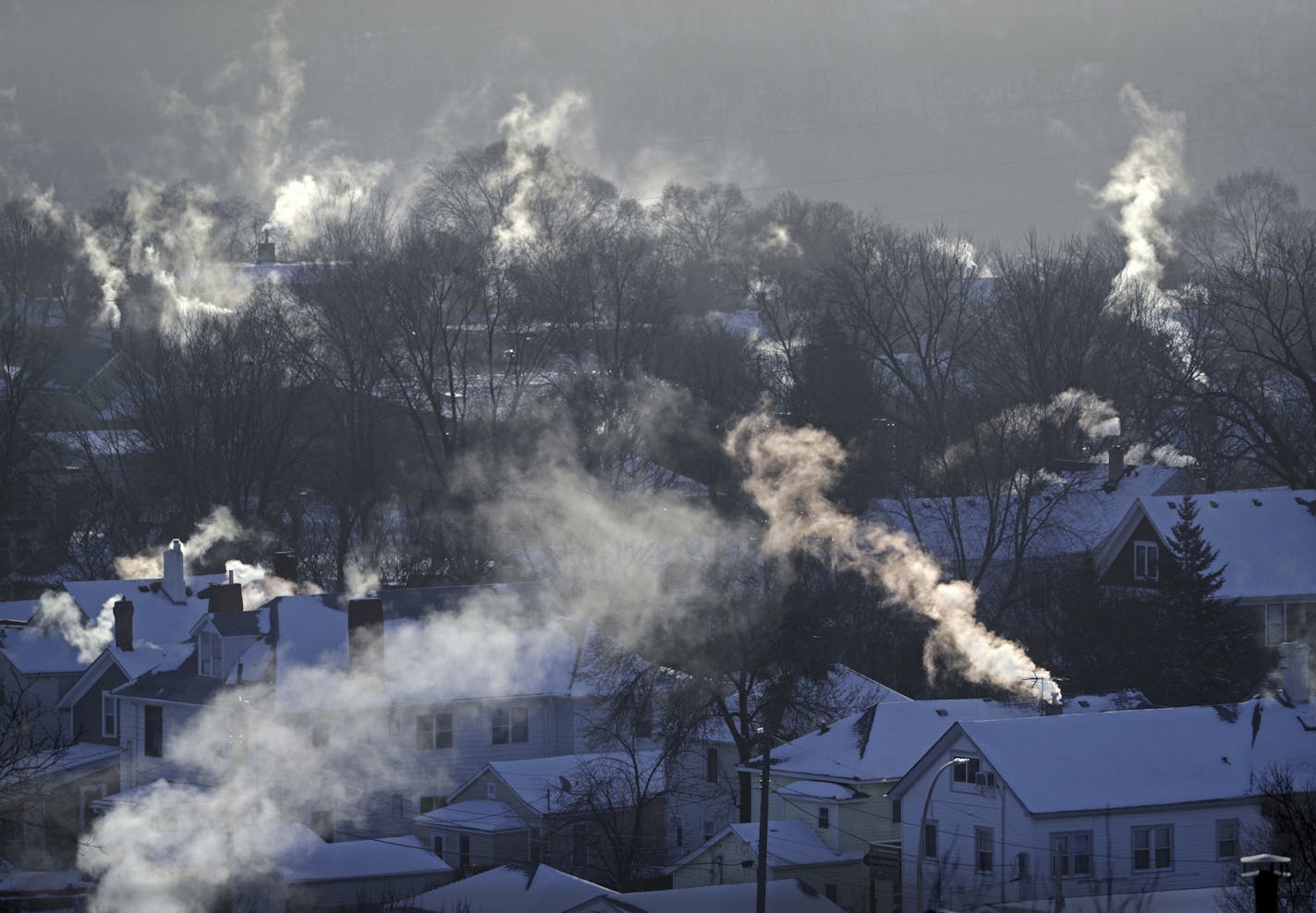 Smoke rises from the chimneys of homes in St. Paul's West 7th neighborhood on Jan. 30, as furnaces tried to keep up with the record breaking cold. Xcel Energy said the extreme cold caused some customers to lose natural gas service in central Minnesota and it had requested customers turn down thermostats during that time. (Brian Peterson/Star Tribune via AP)