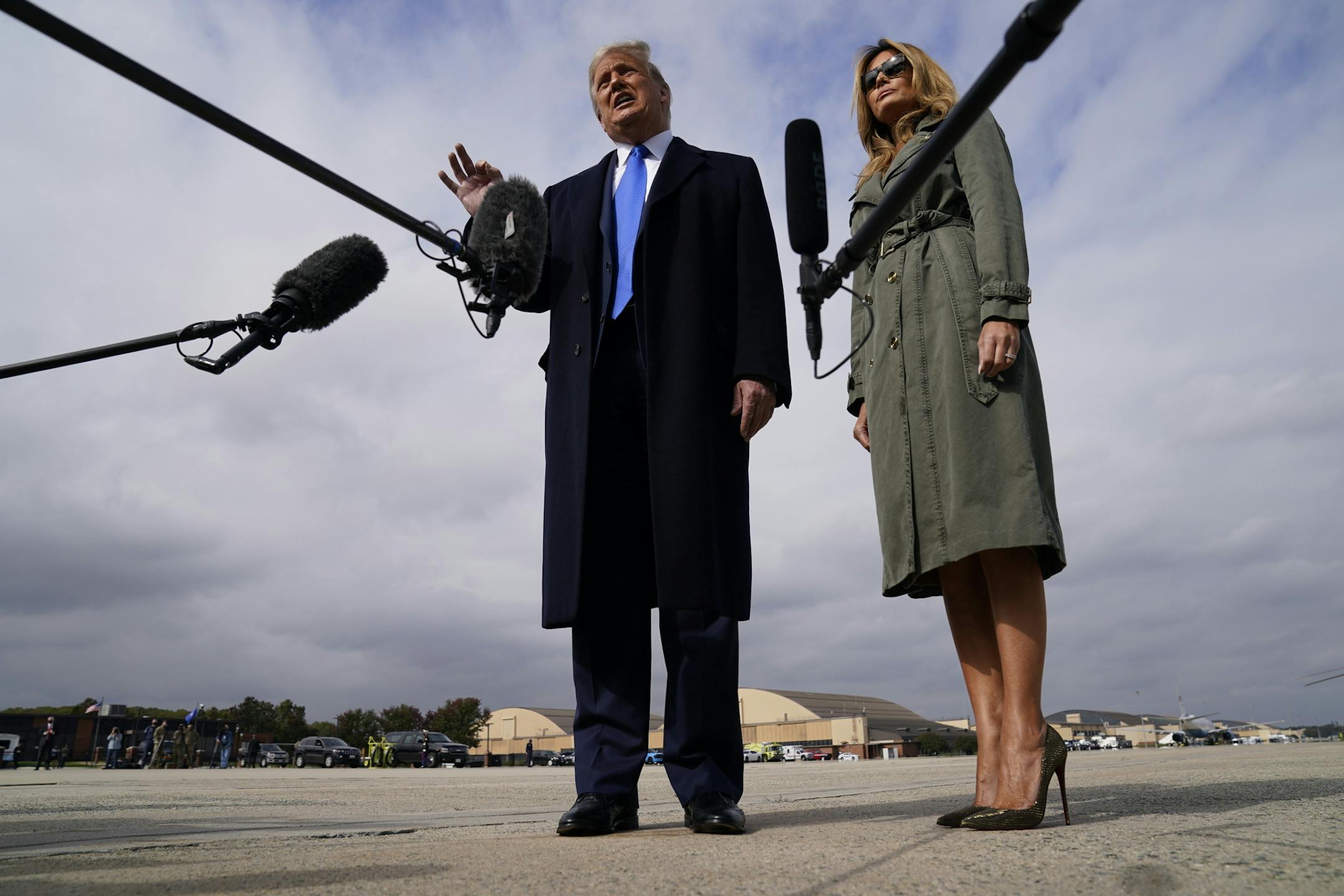 President Donald Trump talks to reporters as first lady Melania Trump listens before boarding Air Force One for a day of campaign rallies in Michigan, Wisconsin, and Nebraska, Tuesday, Oct. 27, 2020, at Andrews Air Force Base, Md. The first lady will be campaigning in Pennsylvania. (AP Photo/Evan Vucci)