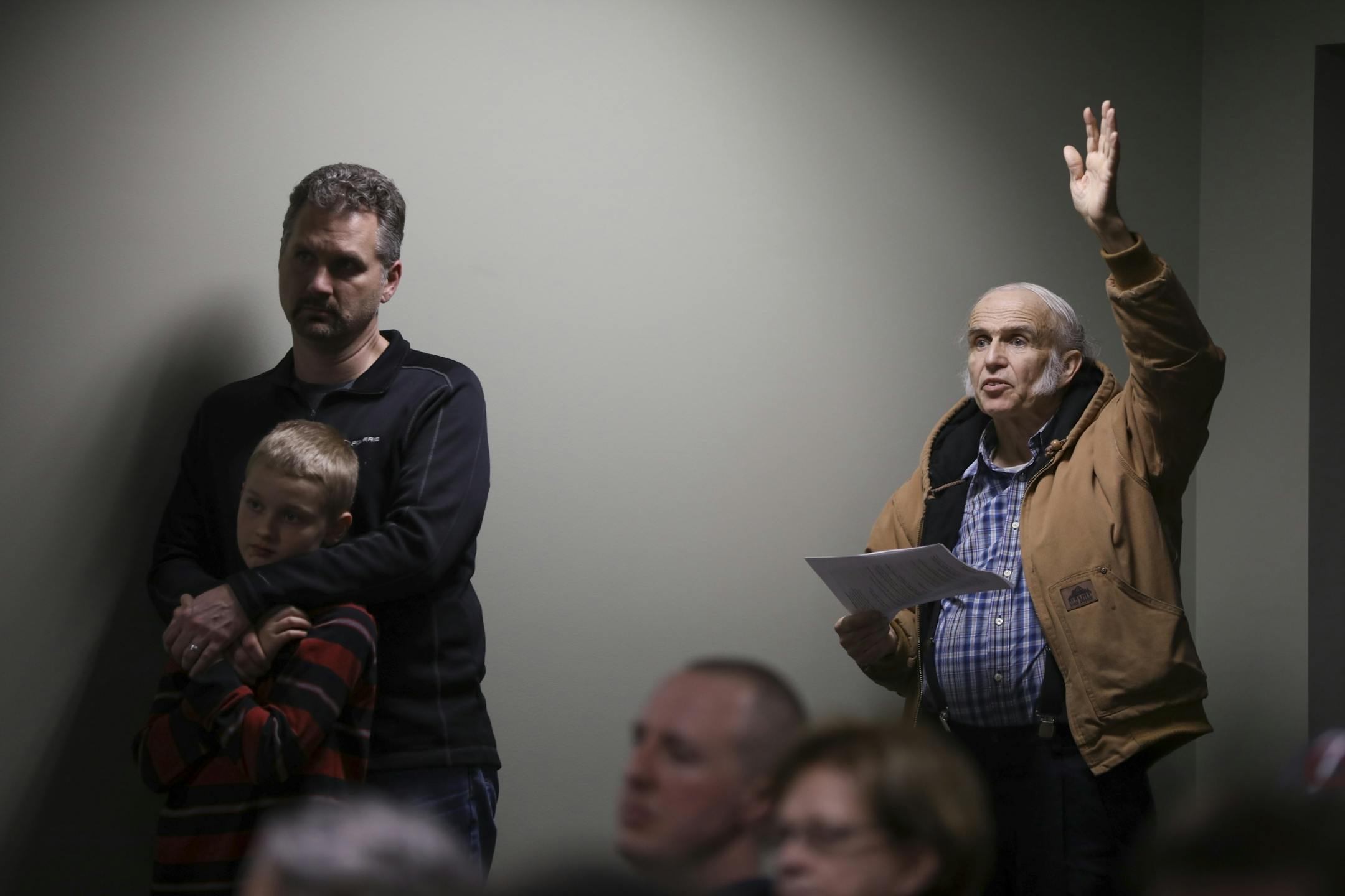 Jason Hoeve with his son, Reece, listened and John Tobako raised his hand to ask a question during the Linwood Township annual meeting Tuesday night.