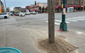 A wooden pole sits in the middle of the sidewalk at the intersection of Lake and Lyndale. Pedestrians will be sidestepping dozens of the temporary pos