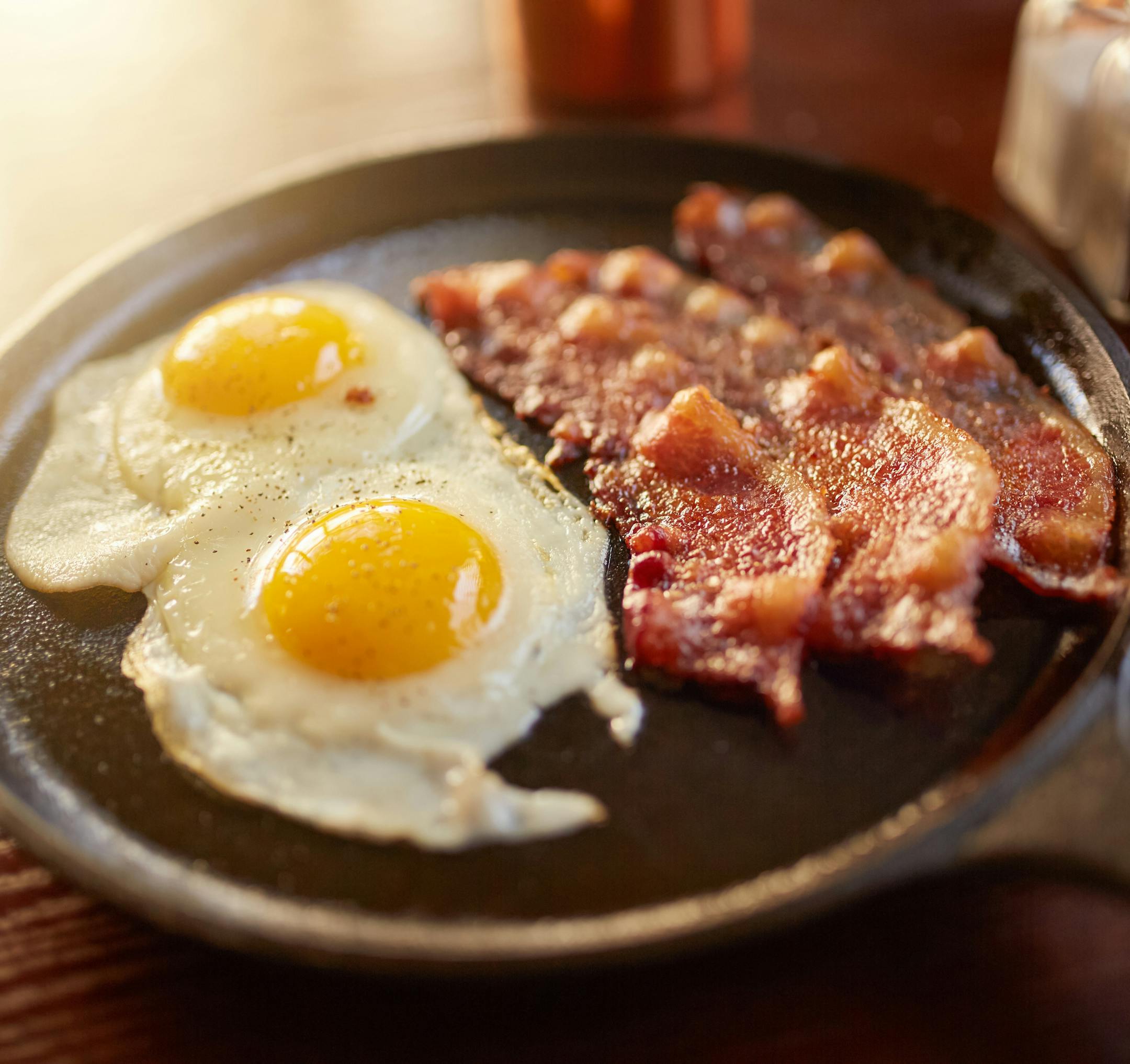 fried bacon and eggs in iron skillet shot with selective focus
