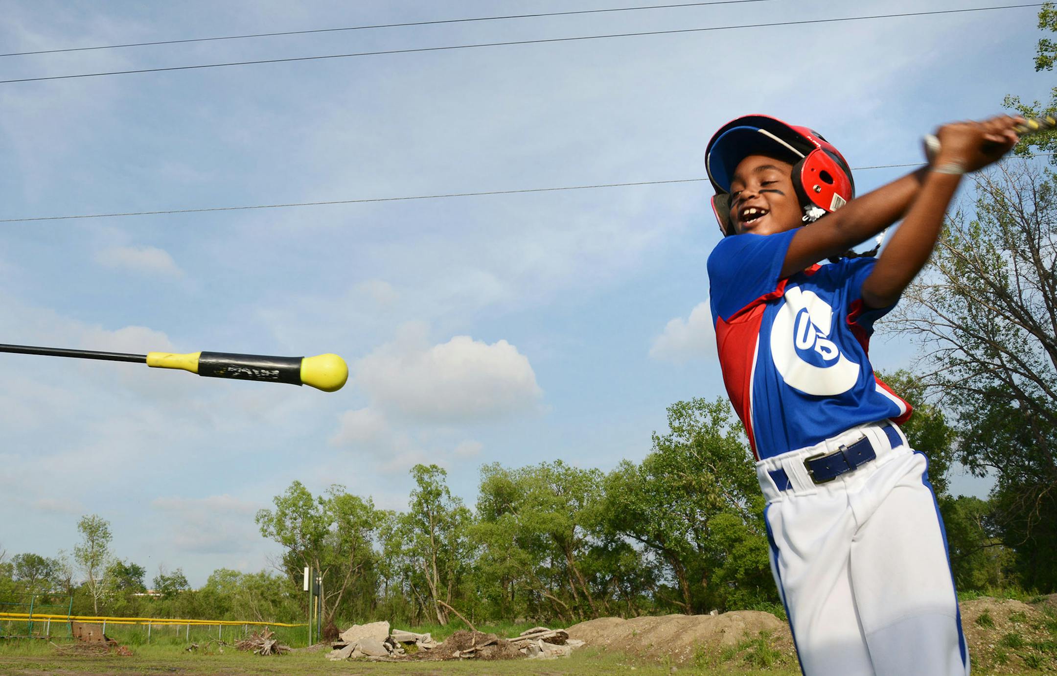Anija Sheffield, 8, of Brooklyn Center, practiced her swing during the Little League Cub's warm-up in Brooklyn Center, Minn., on Thursday June 4, 2015. Behind Sheffield, mounds of dirt and concrete sat next to the little league baseball diamond. The site has become an illegal dumpsite containing concrete and mounds of dirt. ] RACHEL WOOLF rachel.woolf@startribune.com ORG XMIT: MIN1506041922290287