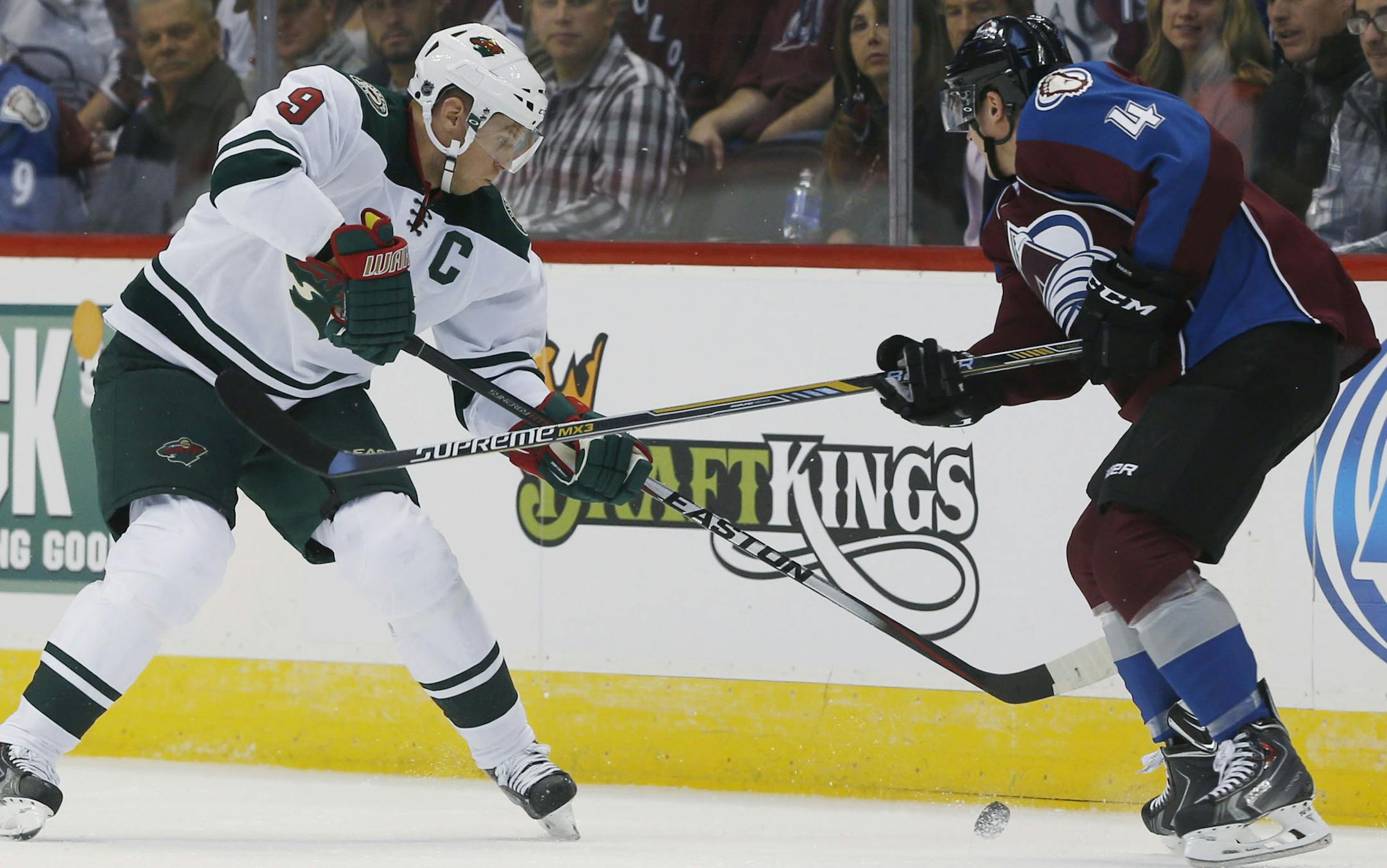 Minnesota Wild center Mikko Koivu, left, of Finland, tries to control the puck as Colorado Avalanche defenseman Tyson Barrie covers in the first period of a hockey game in Denver on Saturday, Oct. 11, 2014. (AP Photo/David Zalubowski)