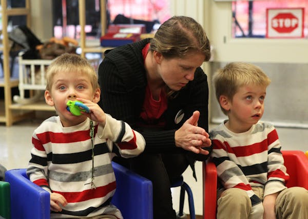Hannah Ostrowski of Redding, a pre-school aide at Buckeye Pre-School in Redding, Calif., works with Dylan Ortiz, 3, left, and his twin, Shane Ortiz, F