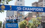 A bus carrying the Golden State Warriors' Kevin Durant and Quinn Cook passed under a champions banner during the team's NBA basketball championship pa