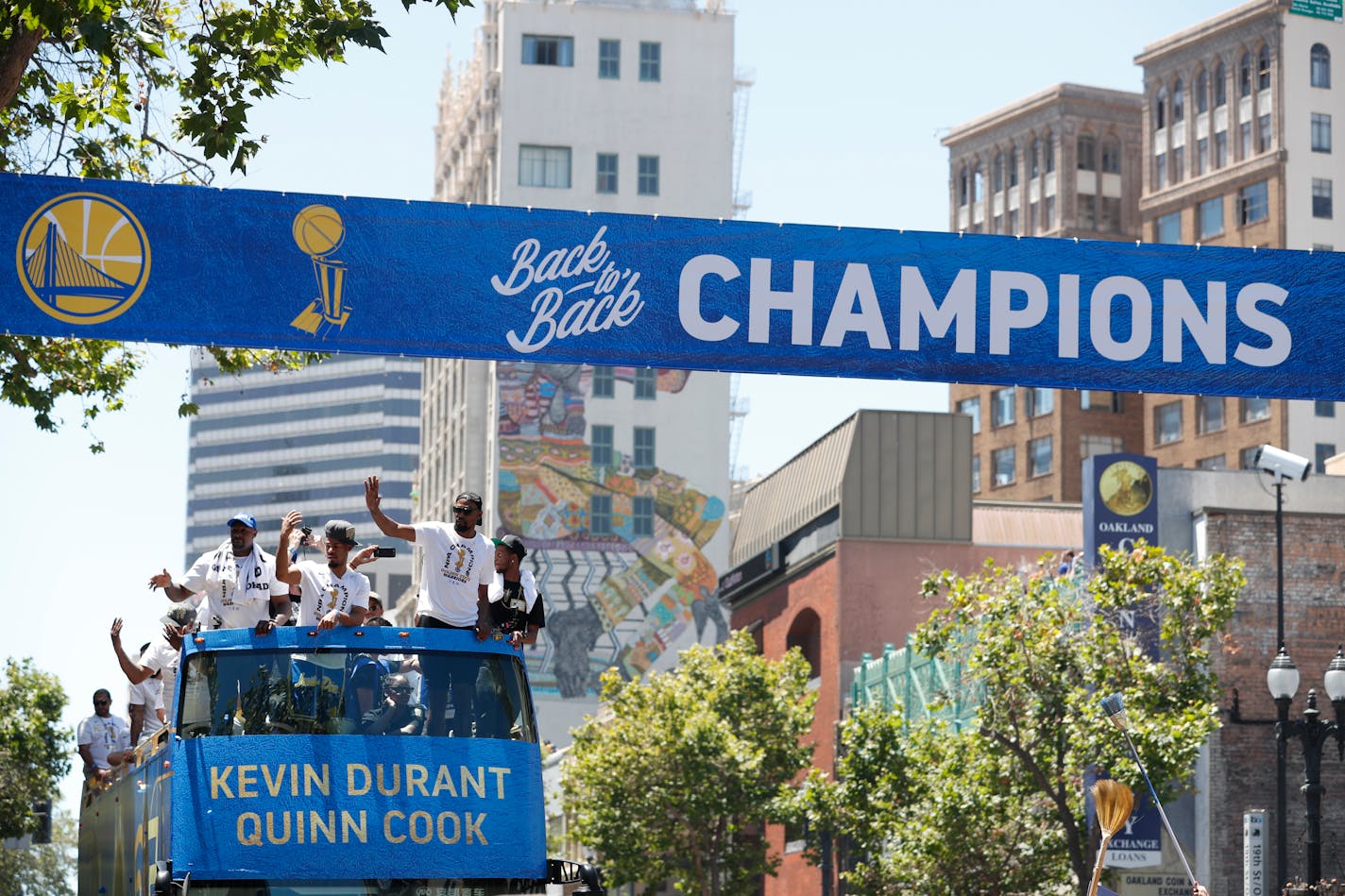 A bus carrying the Golden State Warriors' Kevin Durant and Quinn Cook passed under a champions banner during the team's NBA basketball championship parade in June.