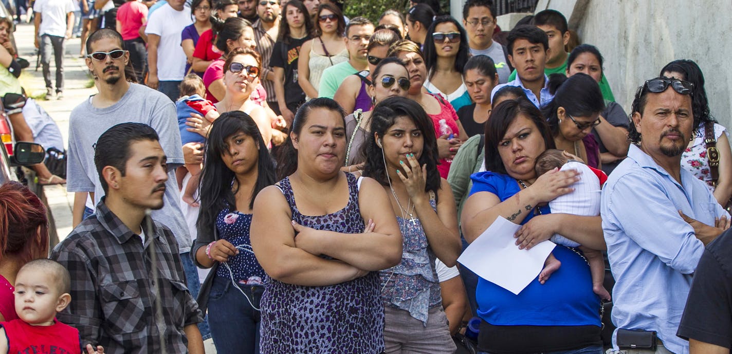 FILE - In this Aug. 15, 2012, file photo, a line of people living in the U.S. without legal permission wait outside the Coalition for Humane Immigrant Rights in Los Angeles. California is suing the Trump administration over its decision to add a question about citizenship to the 2020 U.S. Census. In announcing the lawsuit Tuesday, March 27, 2018, California Attorney General Xavier Becerra says adding such a question is a reckless decision that would violate the U.S. Constitution and cause a popu