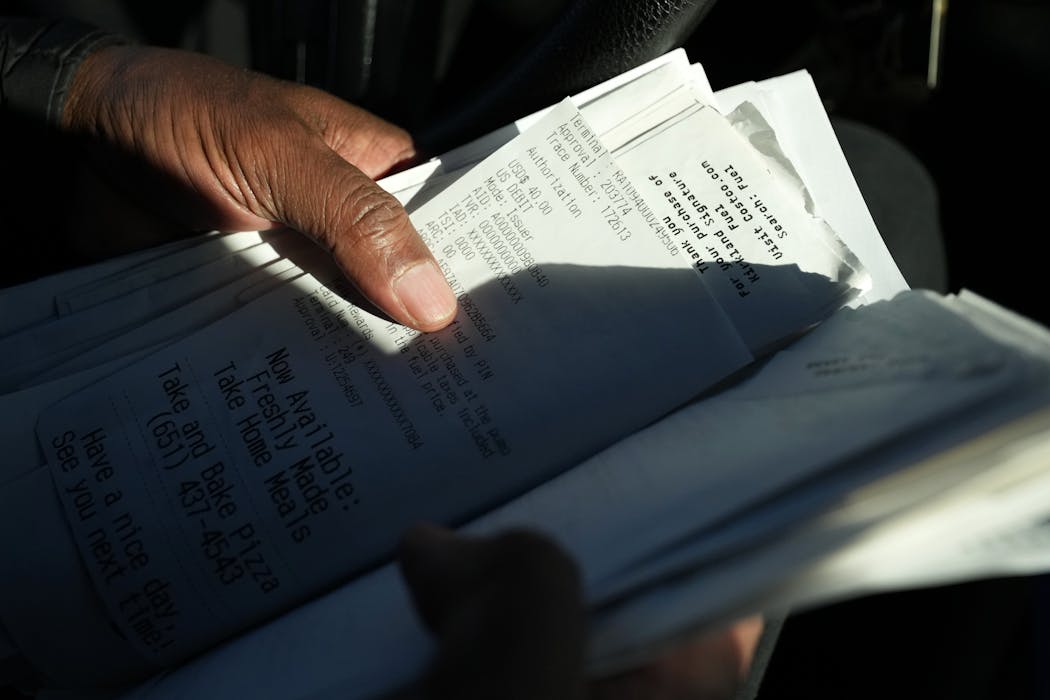 Uber driver Mohamed Egal thumbs through a folder of expense receipts he keeps on Feb. 16 in Minneapolis.
