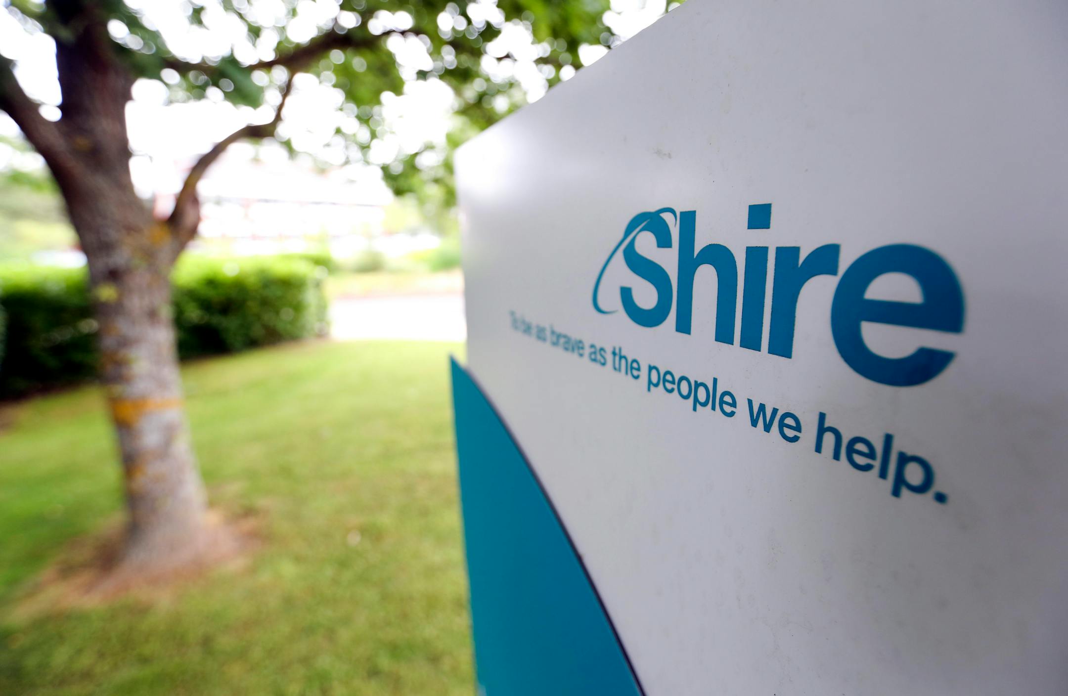 A Shire logo sits on a sign outside office buildings at Shire Plc's site in Chineham, U.K., on Friday, June 27, 2014. AbbVie Inc. said its $46.5 billion bid for Shire offers "compelling" value for Shire shareholders and that it won't rule out going hostile in its drive to acquire the drugmaker. Photographer: Chris Ratcliffe/Bloomberg