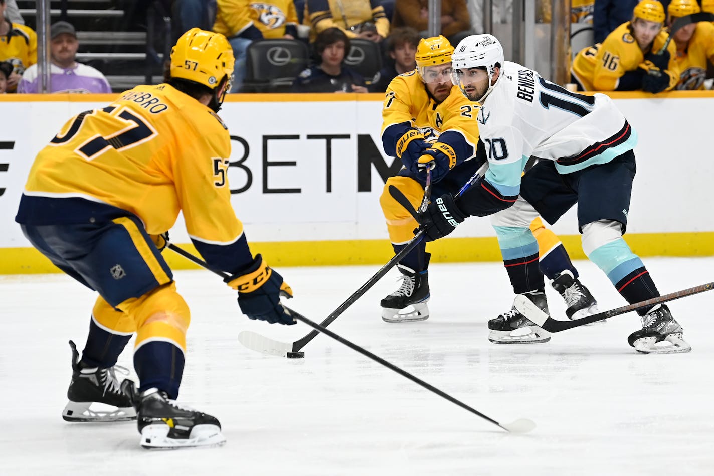 Seattle Kraken center Matty Beniers (10) maneuvers the puck between Nashville Predators' Dante Fabbro (57) and Ryan McDonagh (27) during the third period of an NHL hockey game Saturday, March 25, 2023, in Nashville, Tenn. The Kraken won 7-2. (AP Photo/Mark Zaleski)