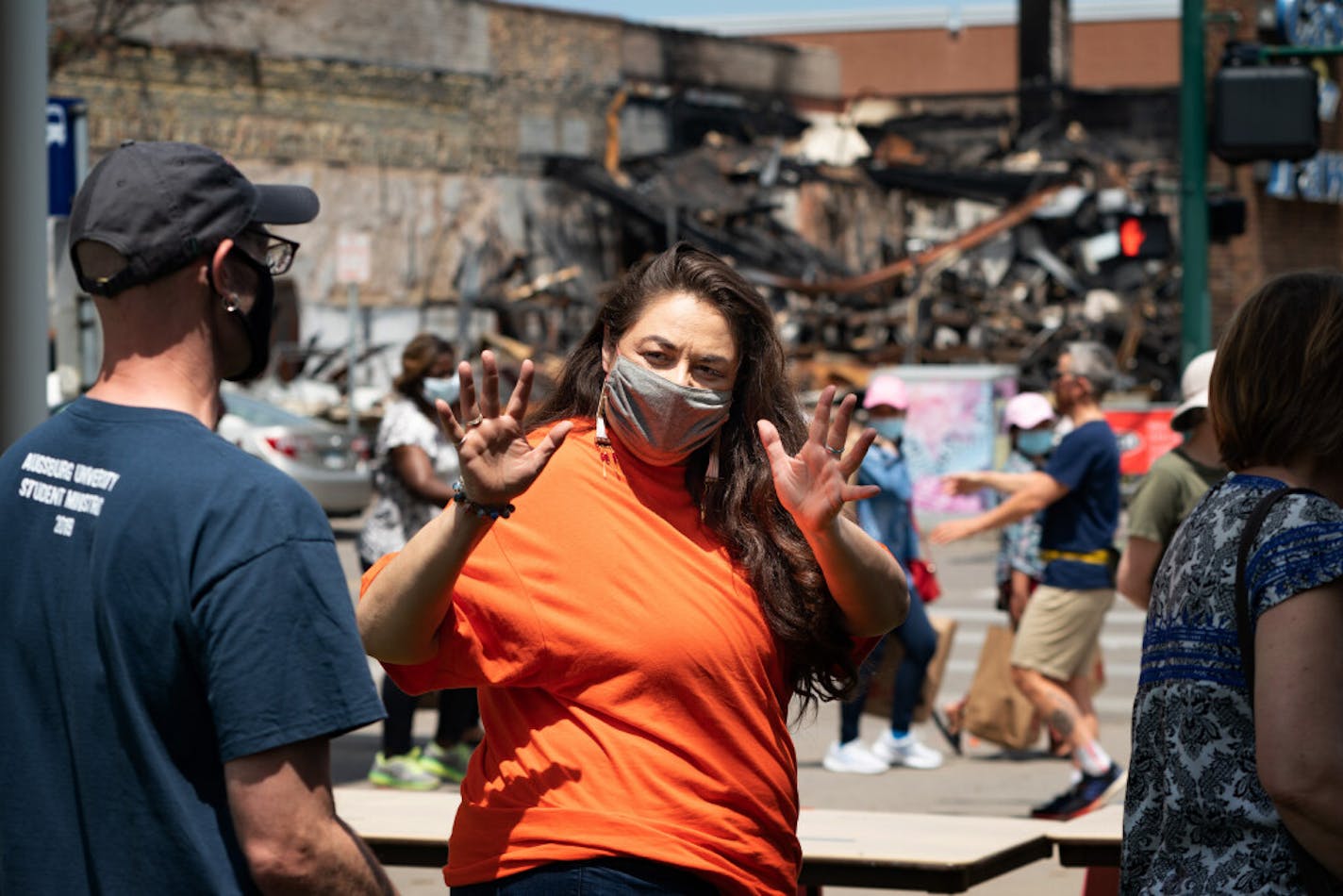 Kelly Sherman-Conroy waved goodbye to one of the volunteer chaplains at Holy Trinity Lutheran Church, which has been a major food distribution site since Lake Street burned. A destroyed pawn shop is across the street.