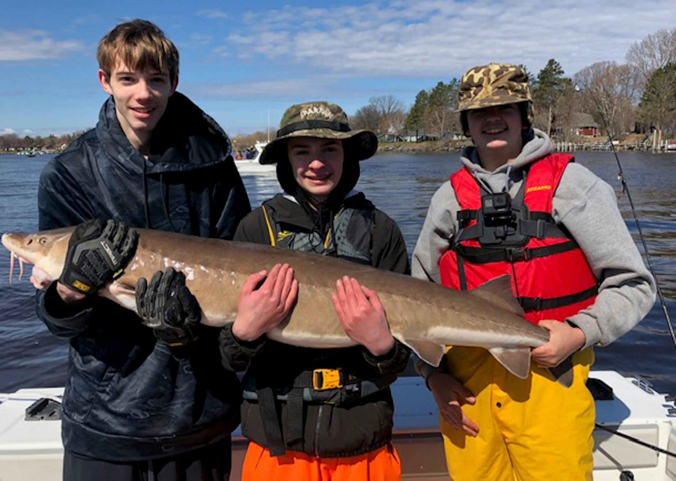 Rick Webster, Braden DePaulis, and Jon Olson, left to right, of the Spartan Angling class with a sturgeon on a class trip.