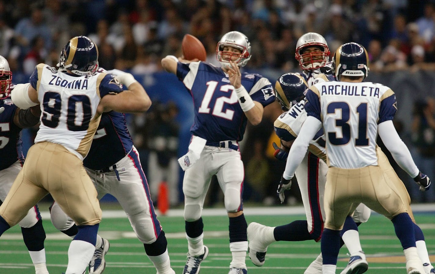 FILE - In this Feb. 3, 2002, file photo, New England Patriots quarterback Tom Brady (12) throws a pass as St. Louis Rams' Jeff Zgonina (90) and Adam Archuleta (31) rush during the third quarter of Super Bowl XXXVI at the Louisiana Superdome in New Orleans. The Patriots are 5-2 in Super Bowls with Tom Brady. So when folks wonder why the spread against Philadelphia is between 5 and 6 points, they should consider that the total difference in scoring in those seven games is 12 points: Patriots 169, opponents 157.