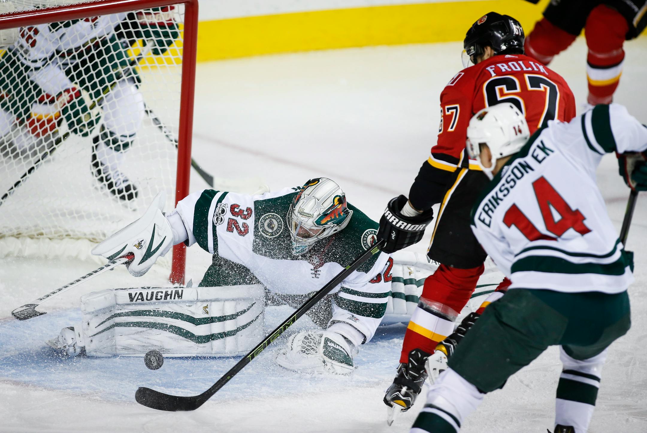 Minnesota Wild goalie Alex Stalock, left, stops Calgary Flames' Michael Frolik, center, from the Czech Republic, as the Wild's Joel Eriksson, from Sweden, watches during the first period of an NHL hockey game Saturday, Oct. 21, 2017, in Calgary, Alberta. (Jeff McIntosh/The Canadian Press via AP)