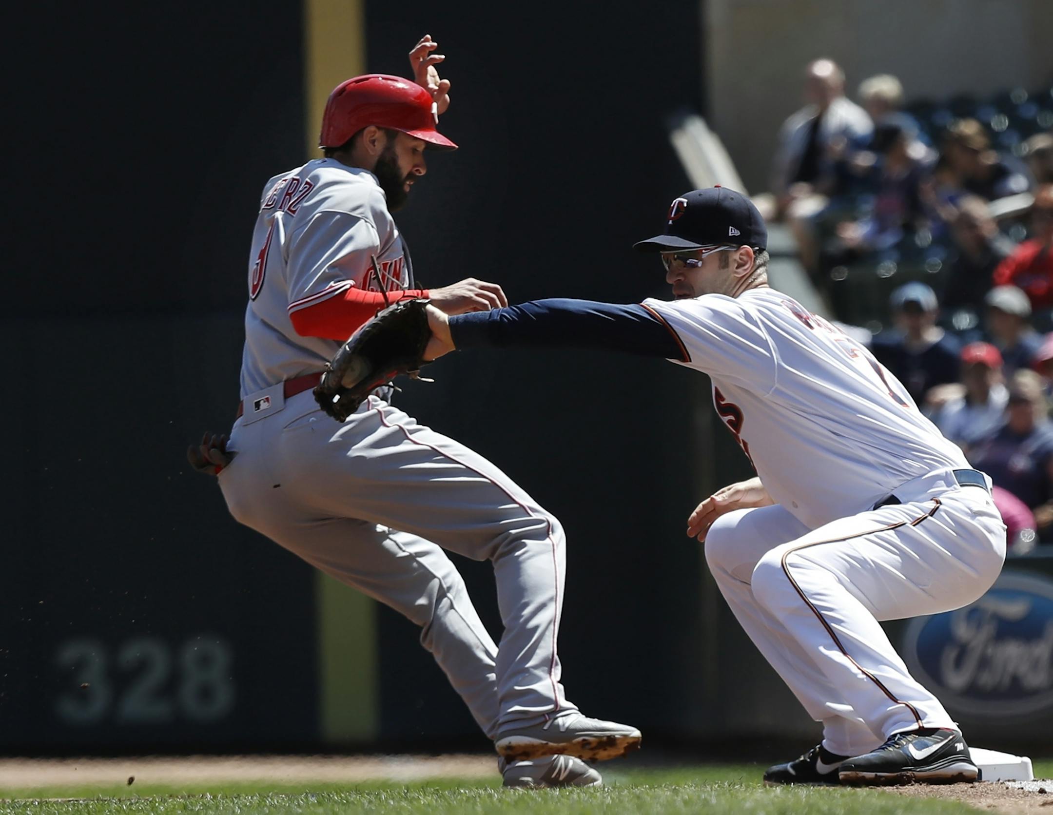 Joe Mauer(7) checks Jose Peraza(9) of the Reds from wandering too far.