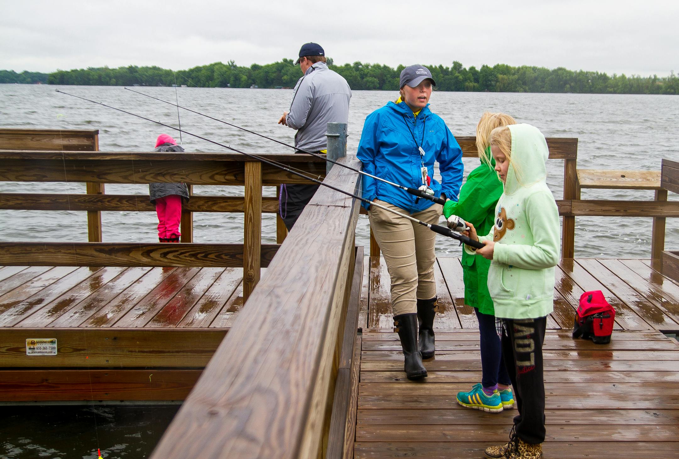 Three Rivers Park District Ashley Brotherton of Burnsville, blue jacket, gives instruction to young anglers Nicole Nohre, 9, and Livia Miller, 8, both of Minneapolis, during a Cleary Lake Regional Park fishing outing on Cedar Lake near New Prague.