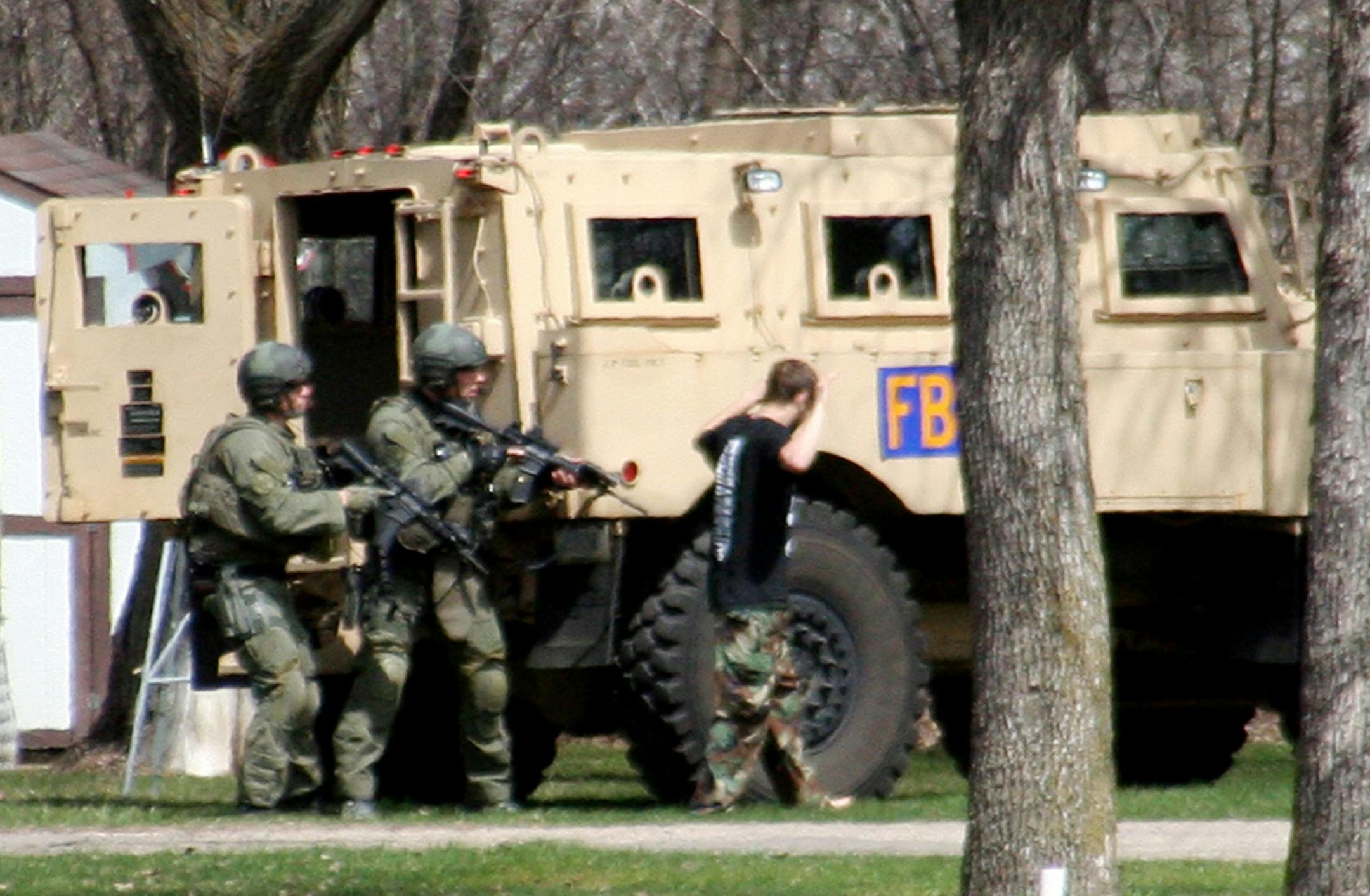 FILE - This May 3, 2013, photo provided by Jeremy Jones shows authorities with Buford Rogers, right, who belongs to a tiny local militia, during a raid on a mobile home in Montevideo, Minn. Rogers, 25, is scheduled to be sentenced Monday, April 28, 2011 after pleading guilty to one count of possessing a firearm illegally and one count of possessing an unregistered destructive device, namely "two black powder and nail devices," which he admitted he made himself. Prosecutors are seeking more than