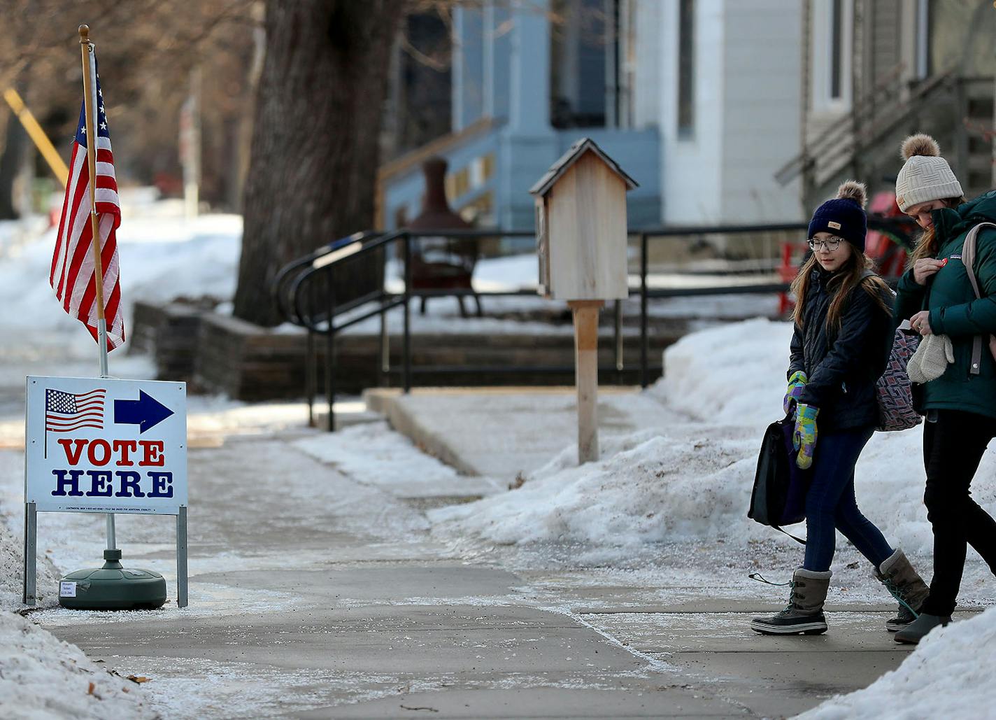 Rebekah Martin places her "I voted" sticker on her jacket after casting her ballot at her polling place at First Congregation Church with her daughter Adelaide, 11, by her side during the Minnesota presidential Primary in Minneapolis. Martin said it isn't the first time her daughter has accompanied her to the polls. "I bring her with me, especially when there are women to vote for," she said.