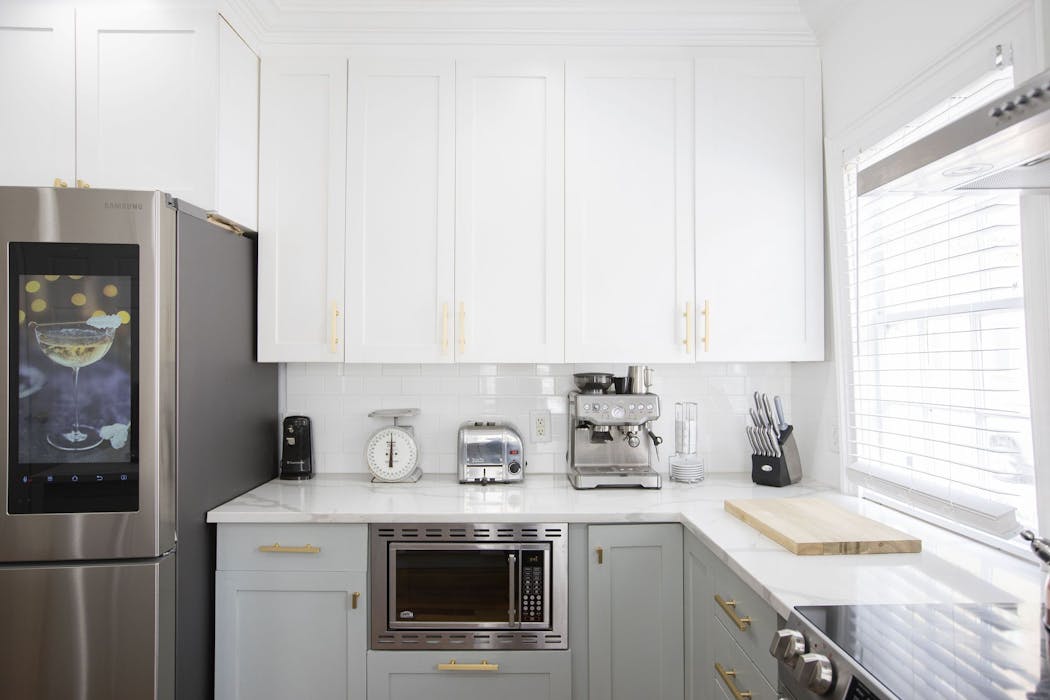 A mix of silver and gold metal finishes adds a fresh vibe to this gray and white kitchen.