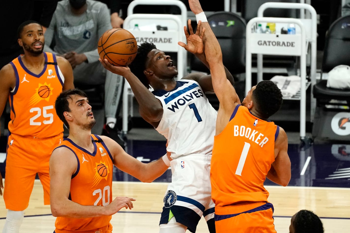 Timberwolves forward Anthony Edwards, front center, drives between Phoenix forward Mikal Bridges (25), forward Dario Saric (20), and guard Devin Booker, right, during the first half