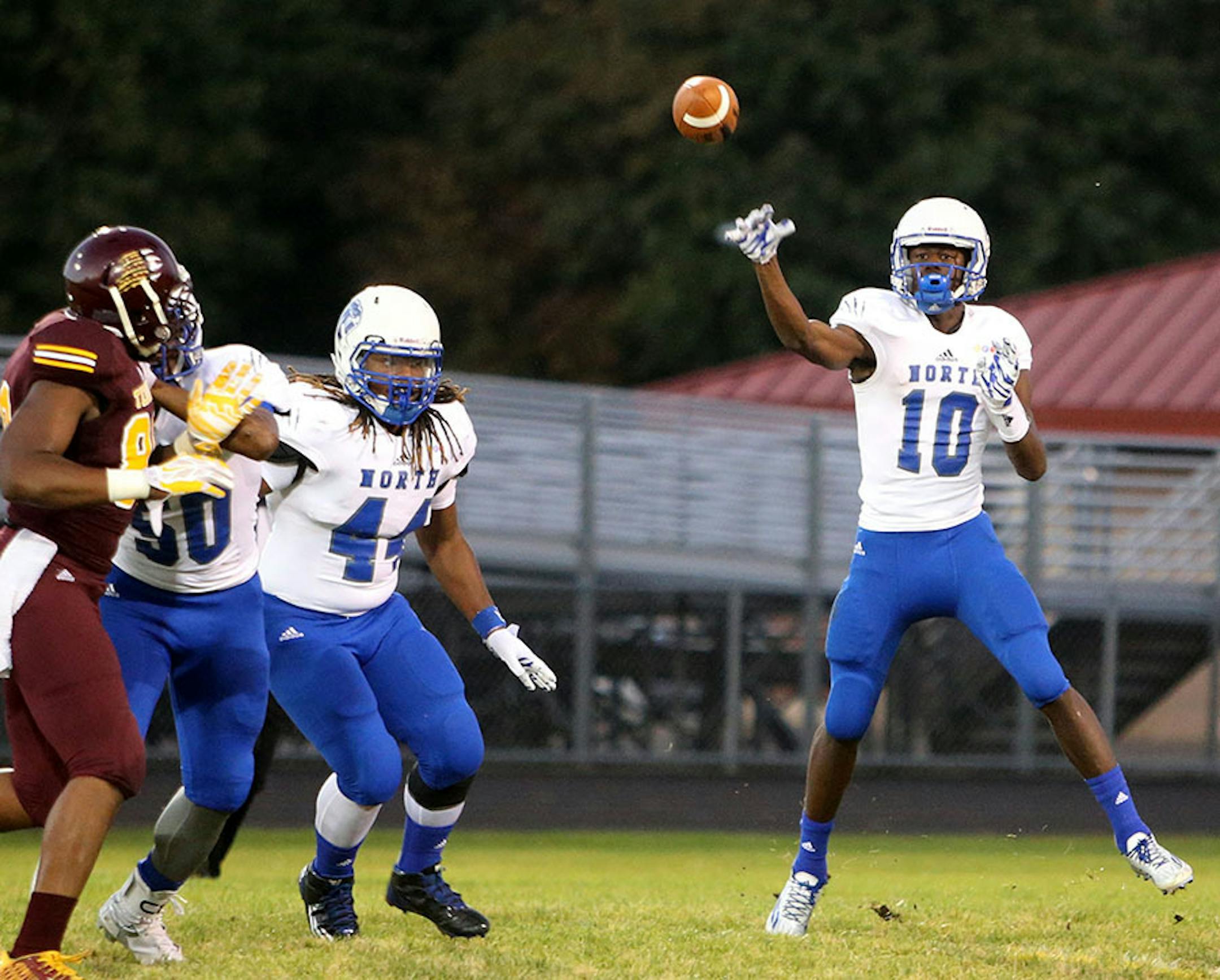Minneapolis North quarterback Tyler Johnson (10) passes upfield with protection from running back Kori Randle (44) during North's 34-12 win over Minneapolis Roosevelt Friday, Sept. 25, in Minneapolis, MN.