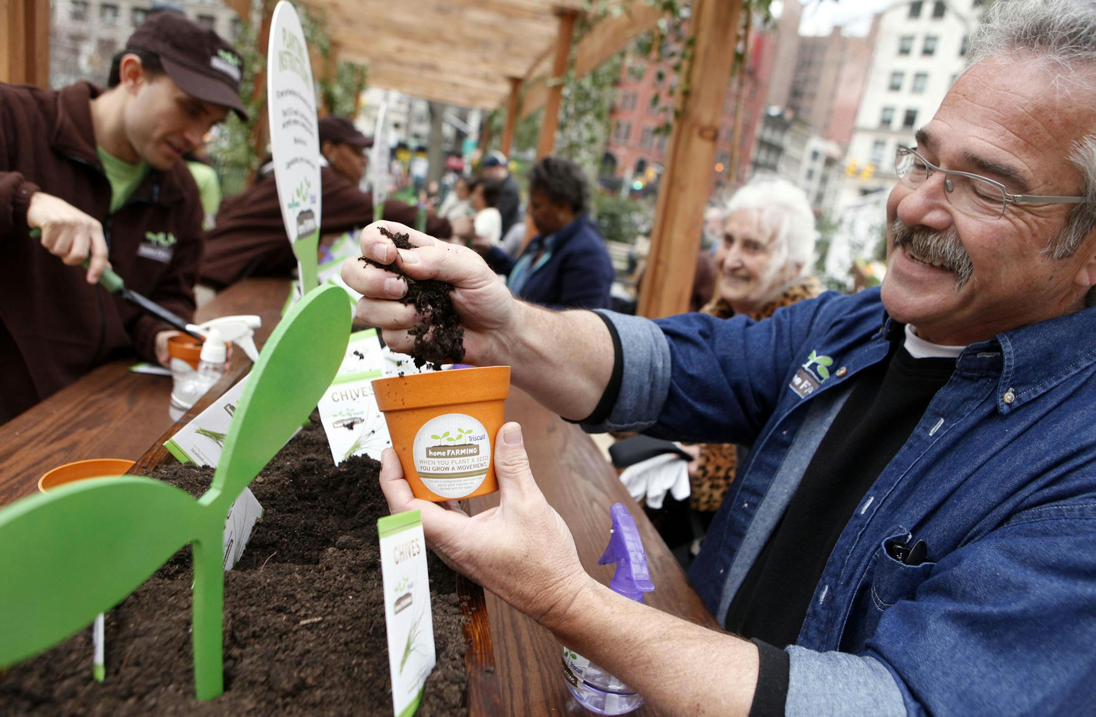 ** COMMERCIAL IMAGE ** In this photo taken by AP Images for Kraft Foods, HGTV's 'The Gardener Guy' Paul James plants with New Yorkers at Triscuit Crackers 'Home Farming Day' celebration in New York's Madison Square Park, Tuesday, April 12, 2011. (Jason DeCrow/AP Images for Kraft Foods) ORG XMIT: CPA203