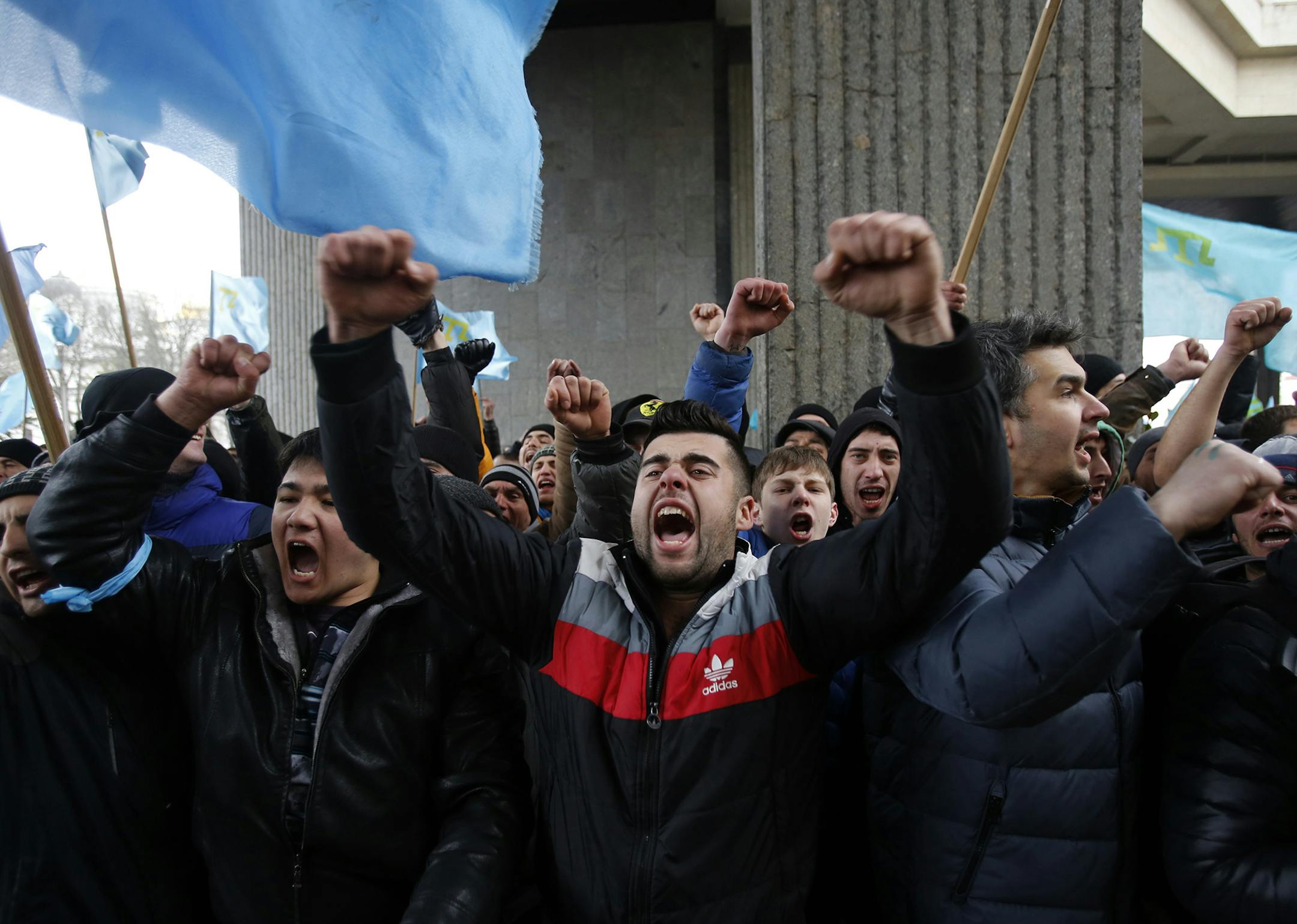 Crimean Tatars shout slogans during a protest in front of a local government building in Simferopol, Crimea, Ukraine, Wednesday, Feb. 26, 2014. More than 10,000 Muslim Tatars rallied in support of the interim government. That group clashed with a smaller pro-Russian rally nearby. Fistfights broke out between pro- and anti-Russian demonstrators in Ukraine's strategic Crimea region on Wednesday as Russian President Vladimir Putin ordered massive military exercises just across the border. (AP Photo