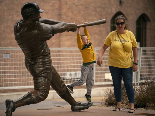 Zach Zimmerman, 5, hung on the bat of the Harmon Killebrew statue for a photo while his mom, Nikki Zimmerman stood nearby before the game against the 