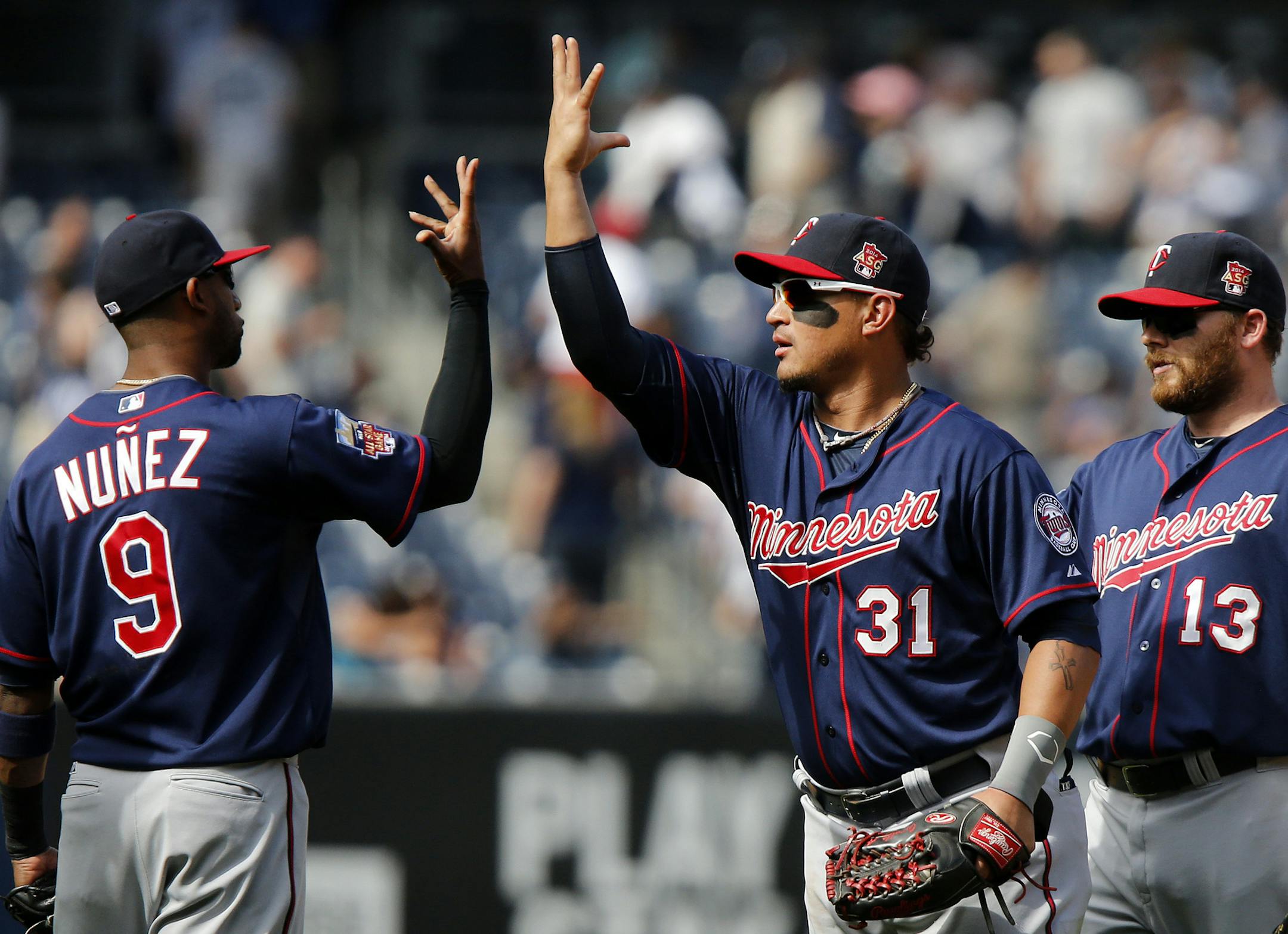 Minnesota Twins' Eduardo Nunez, left, celebrates with Oswaldo Arcia, center, as teammate Jason Kubel looks on after winning a baseball game against the New York Yankees, Sunday, June 1, 2014, in New York. Minnesota won 7-2. (AP Photo/Jason DeCrow)