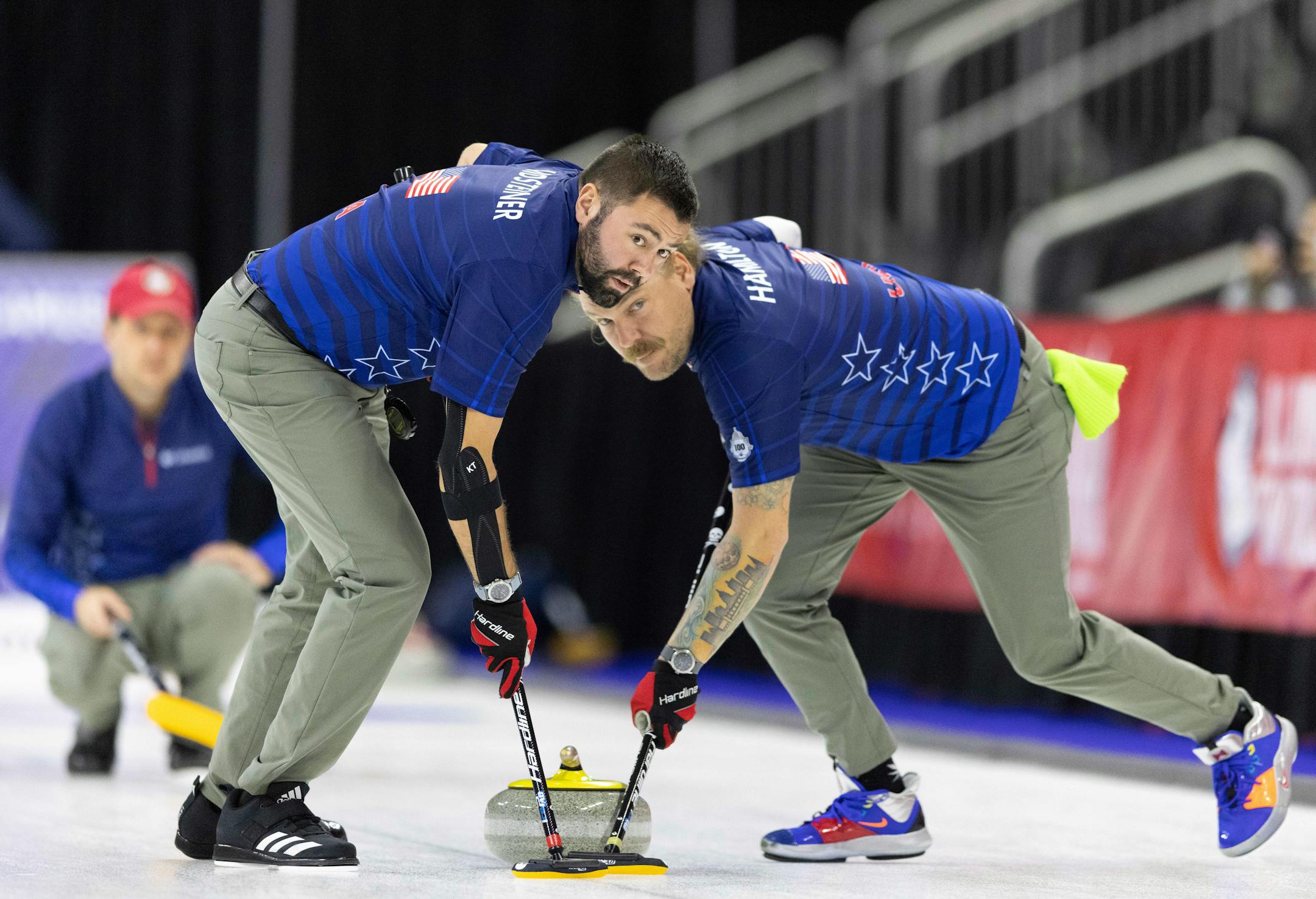 Team Shuster's John Landsteiner, left, and Matt Hamilton sweep to curl the rock while competing against Team Brundidge at the U.S. Olympic Curling Team Trials at Baxter Arena in Omaha, Neb., Thursday, Nov. 18, 2021. (AP Photo/Rebecca S. Gratz)