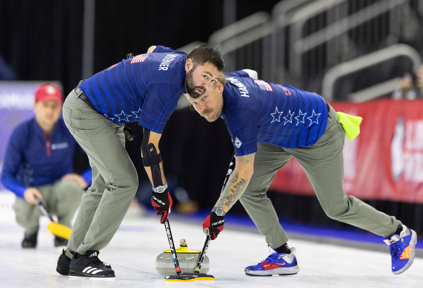 Team Shuster's John Landsteiner, left, and Matt Hamilton sweep to curl the rock while competing against Team Brundidge at the U.S. Olympic Curling Team Trials at Baxter Arena in Omaha, Neb., Thursday, Nov. 18, 2021. (AP Photo/Rebecca S. Gratz)