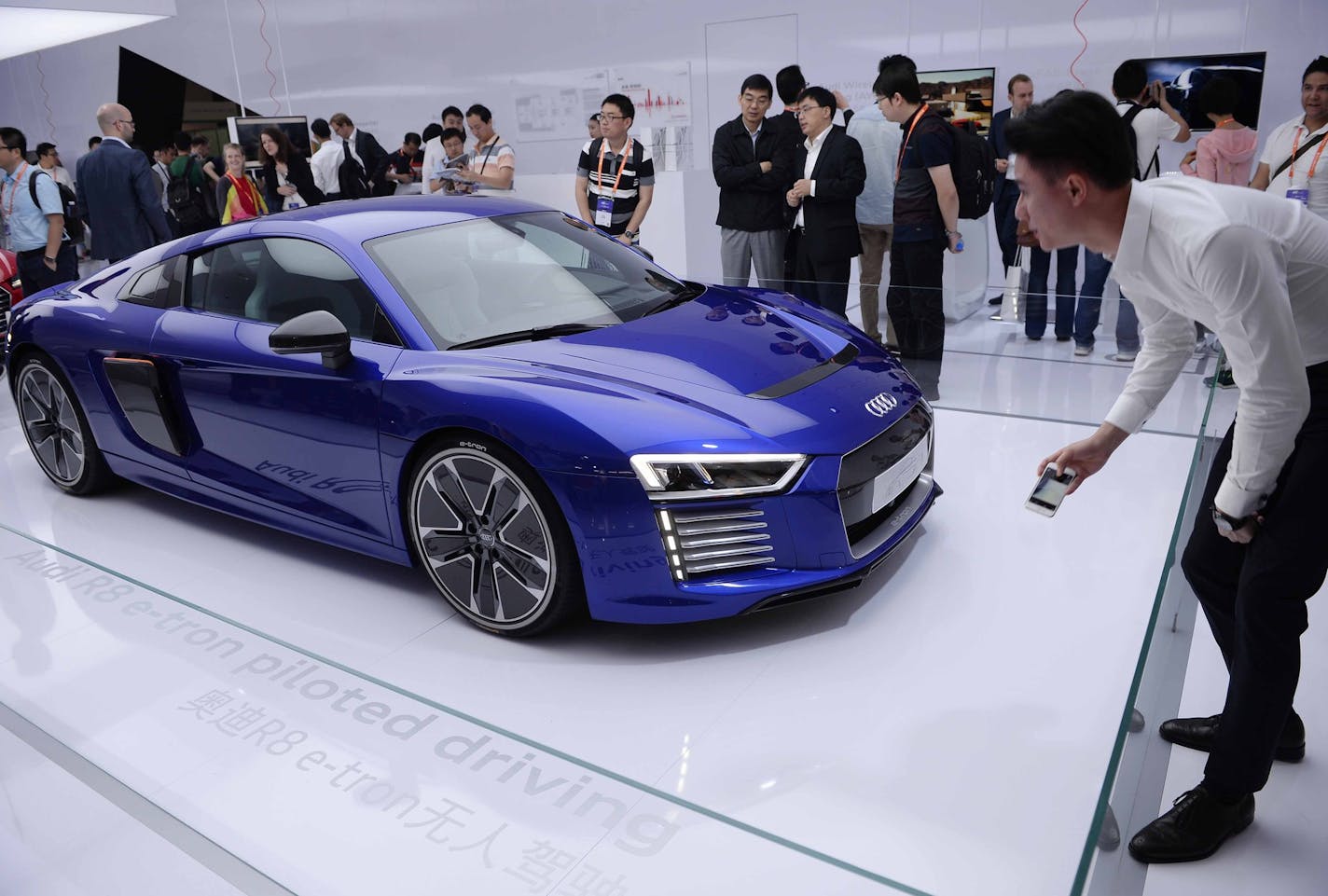 Visitors look at the Audi R8 e-tron, a driverless electronic car, as it is displayed at the inaugural International Consumer Electronics Show (CES) Asia in Shanghai, Tuesday, May 26, 2015. The well-known electronics trade show is being held in Asia for the first time. (Chinatopix Via AP) CHINA OUT