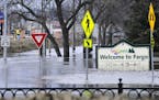FILE - In this April 8, 2011 file photo, a welcome sign for Fargo, N.D., sits in the rising floodwaters of the Red River as a flood engineer for the U