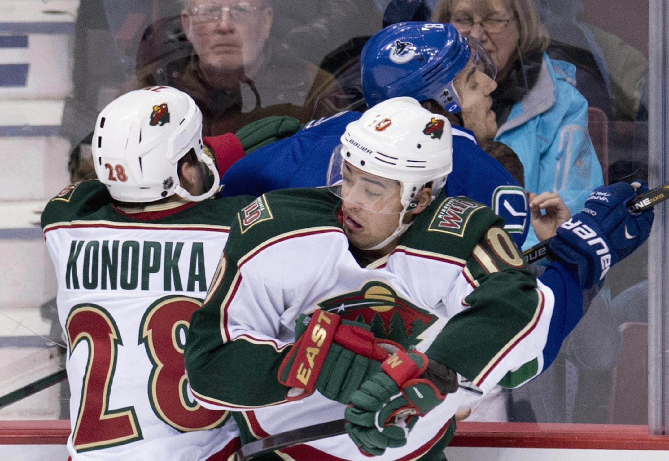 Minnesota Wild center Zenon Konopka (28) and Minnesota Wild right wing Devin Setoguchi (10) put Vancouver Canucks defenseman Chris Tanev (8) into the boards during first period NHL hockey action at Rogers Arena in Vancouver, British Columbia Monday, March,18, 2013.