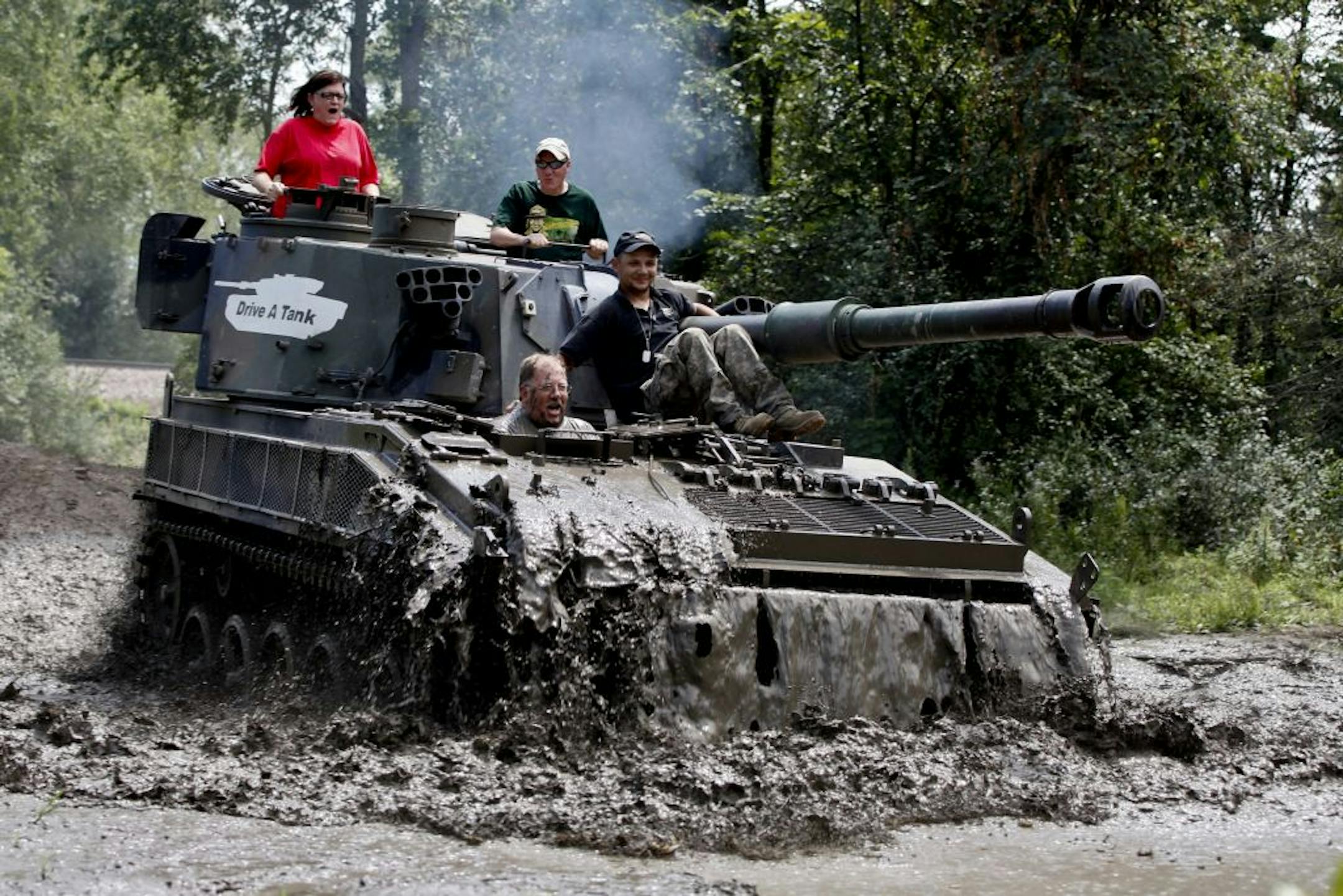 Todd Holmes of Lino Lakes enjoyed the effects of driving through a mud puddle with guidance from Drive a Tank employee Roman Petersen, right.