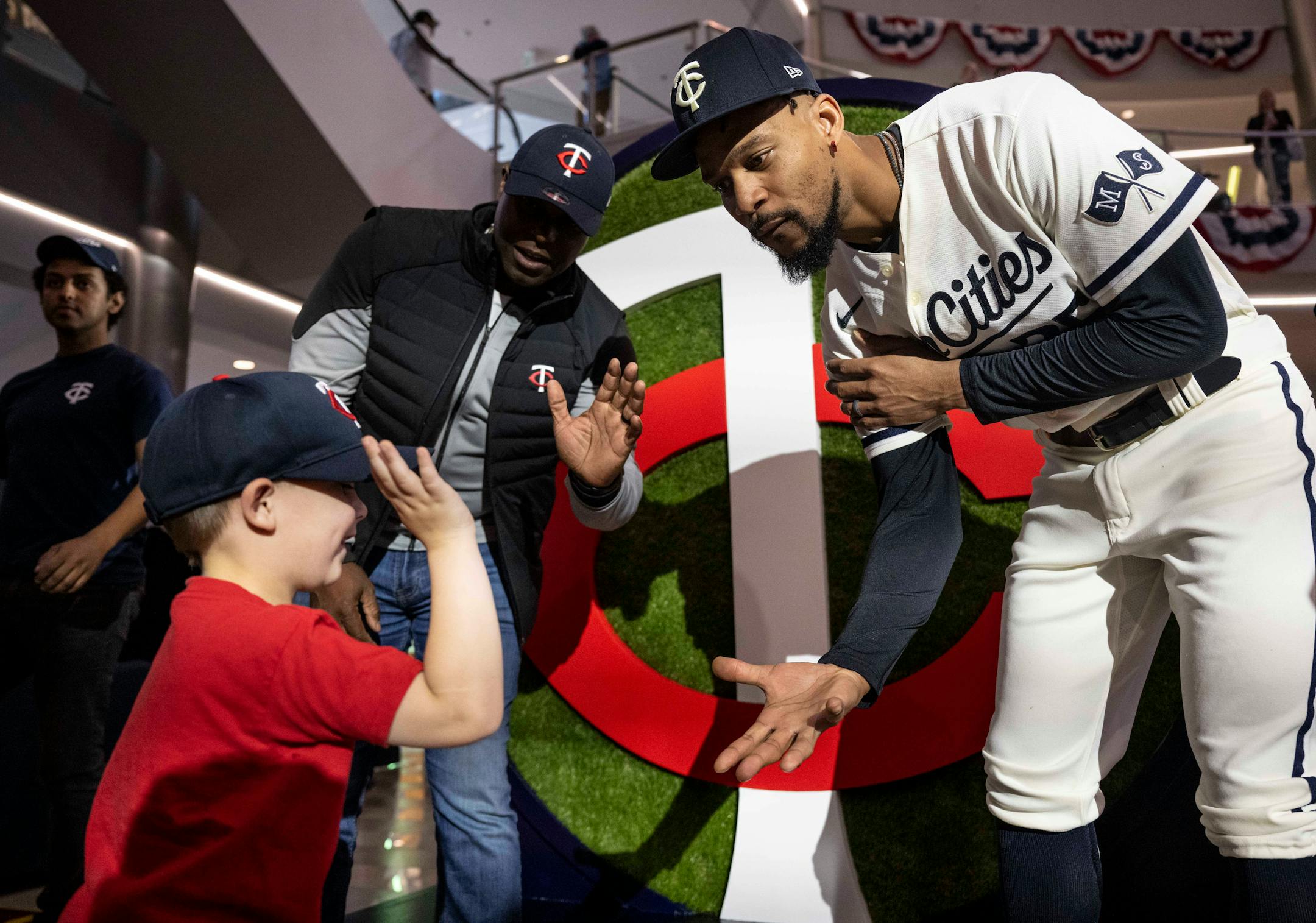 Anders Hatch, 5, of Lakeville, high fives Minnesota Twins center fielder Byron Buxton (25) and Twins Hall-of-Famer Torii Hunter, back left, after the Twins unveiled their new logo and jerseys.