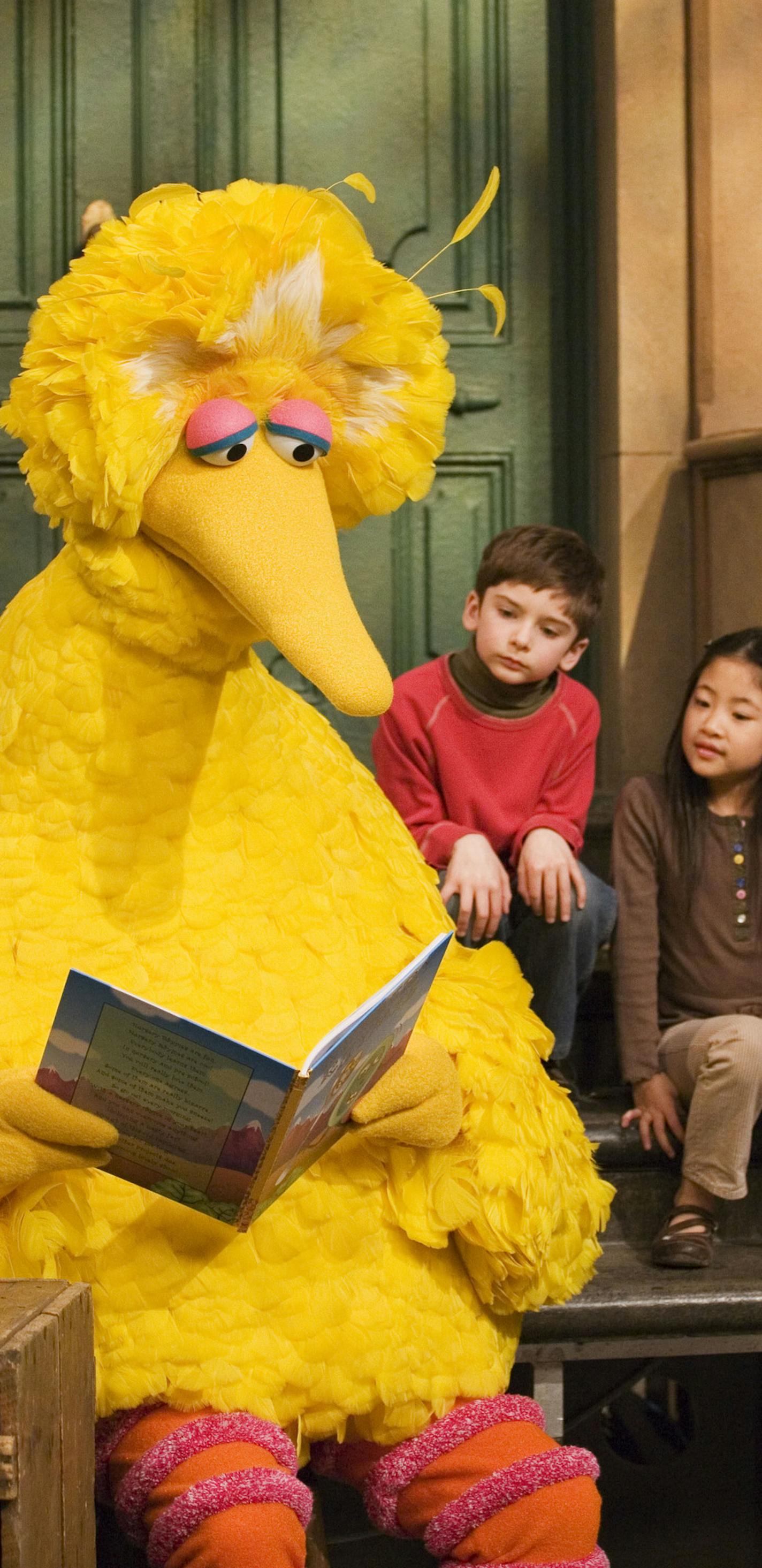 FILE - In this April 10, 2008 file photo, Big Bird, voiced by Carroll Spinney, reads to Connor Scott and Tiffany Jiao during a taping of Sesame Street in New York. Spinney drops his fine-feathered obscurity (and emerges from his garbage-can fortress as Oscar the Grouch) for an enchanting film portrait, "I Am Big Bird: The Caroll Spinney Story," which celebrates the "Sesame Street" puppet master who, at age 81, continues to breathe life into a pair of the world's best-loved personalities. (AP Pho