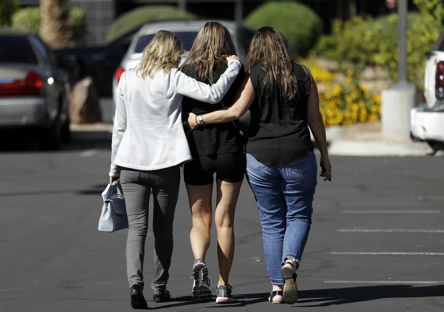 Kris Delarosby, right, and Colleen Anderson hold Charleen Jochim, center, as they walk toward a Las Vegas hospital in search of information on a missing friend, Steve Berger of Shorewood, Minn. Berger died in the shooting.