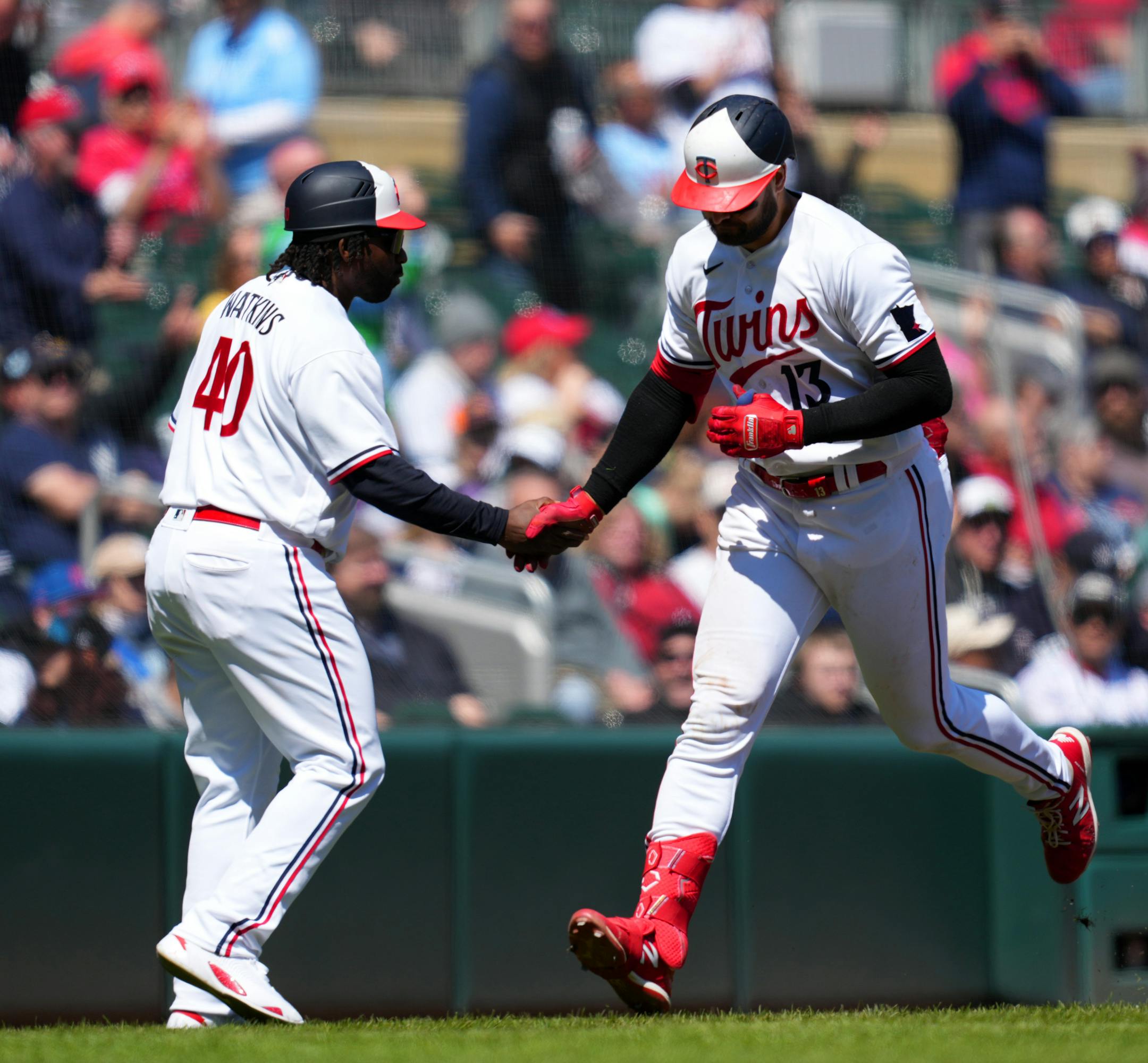 Minnesota Twins first baseman Joey Gallo (13) celebrates with third base coach Tommy Watkins (40) as he rounds the bases after hitting a solo home run in the sixth inning.